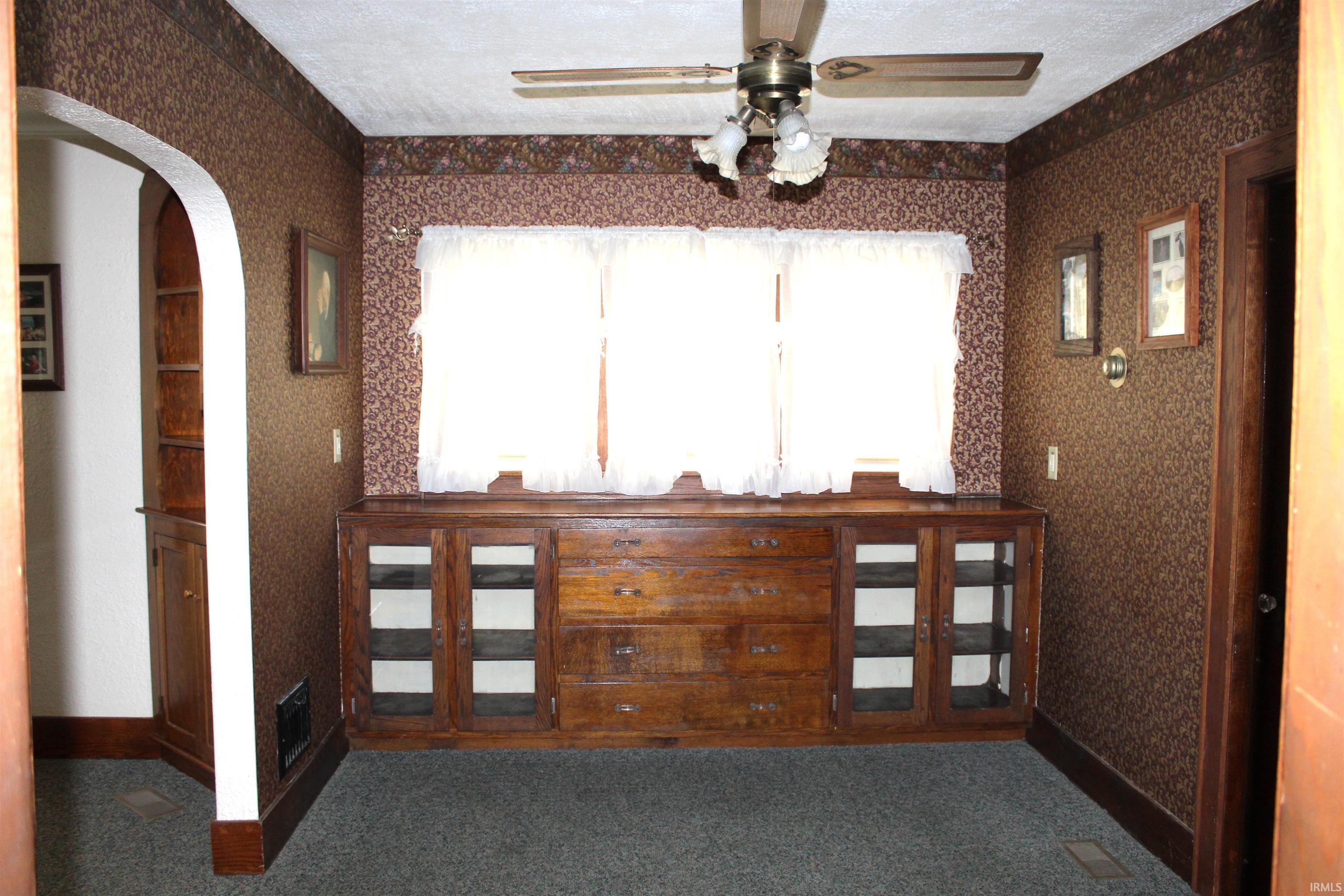 Built-in wood-finish cabinetry featuring drawers and glass-front display cabinets under a triple window