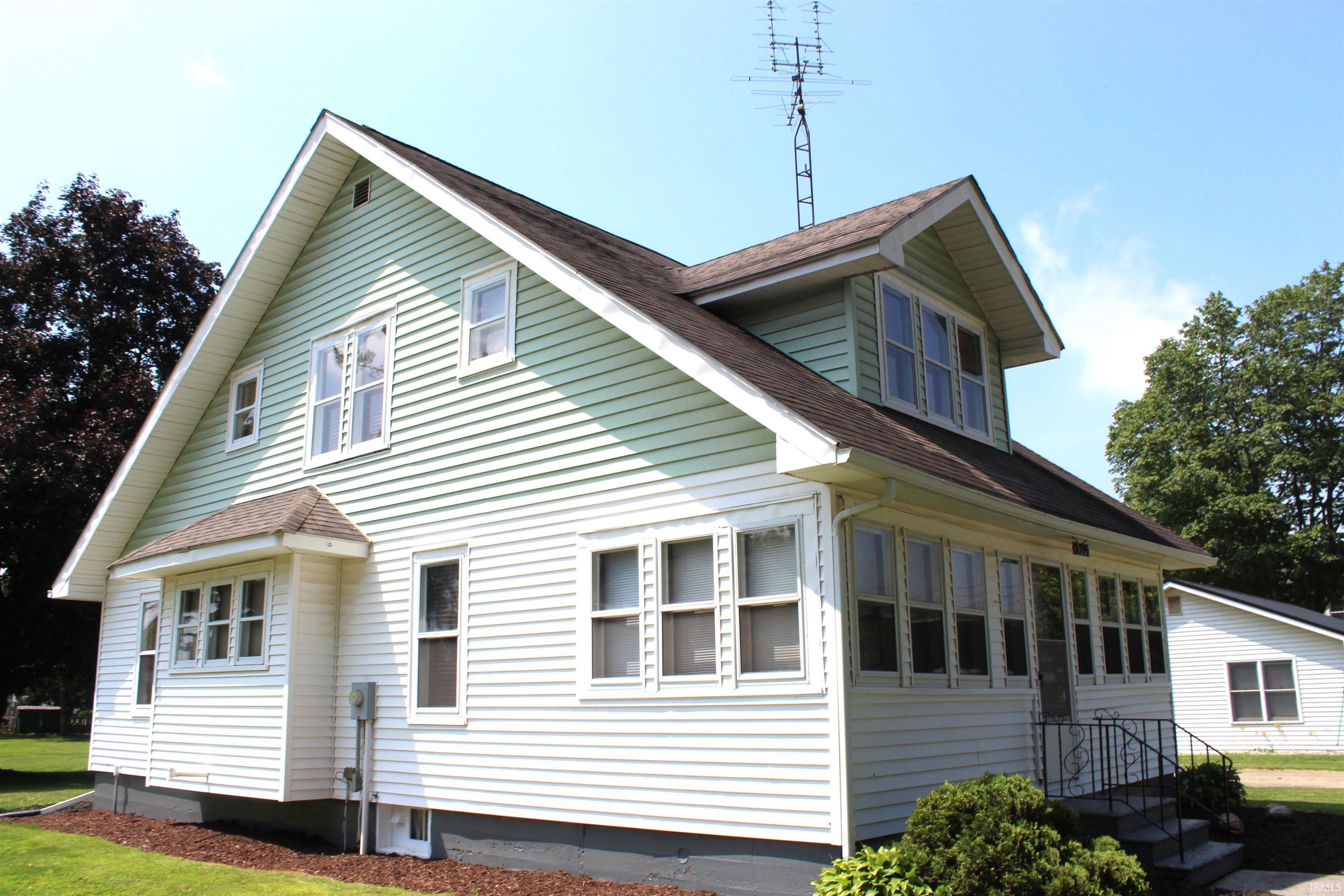 Two-story property featuring light green and white siding, a contrasting dark roof, and multiple windows across both levels