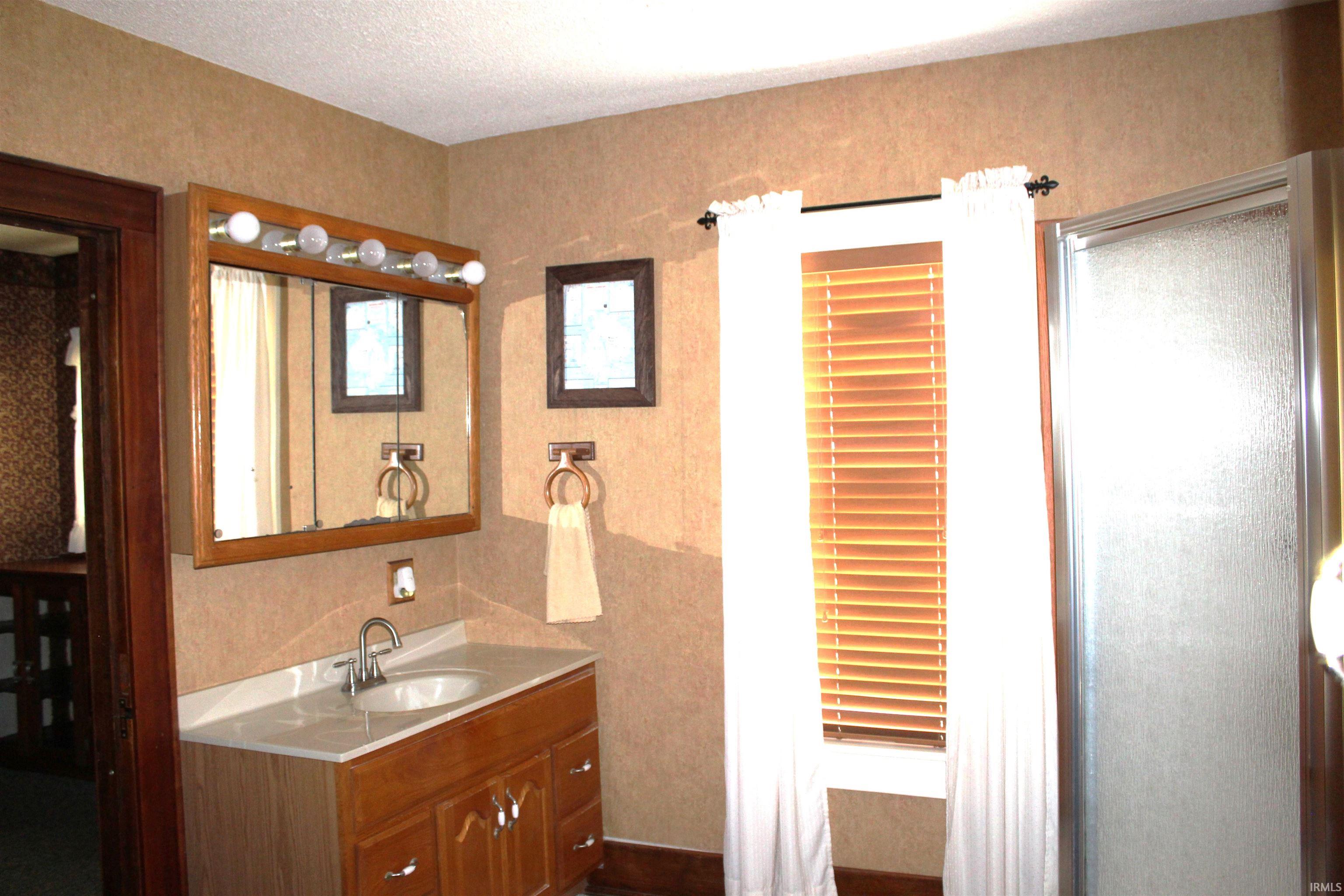 Bathroom featuring a wood-finish vanity with a single basin sink and light-colored countertop