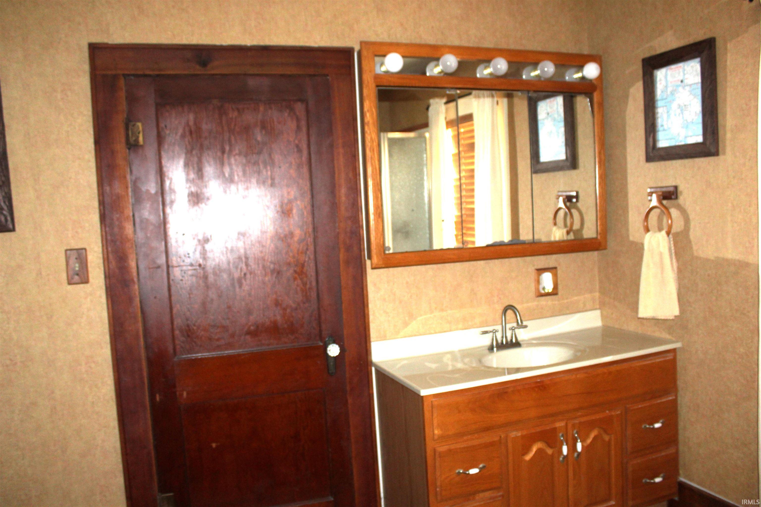 Bathroom vanity featuring a light-colored countertop with an undermount sink, a chrome faucet, and a wood-finish base cabinet with multiple drawers and doors
