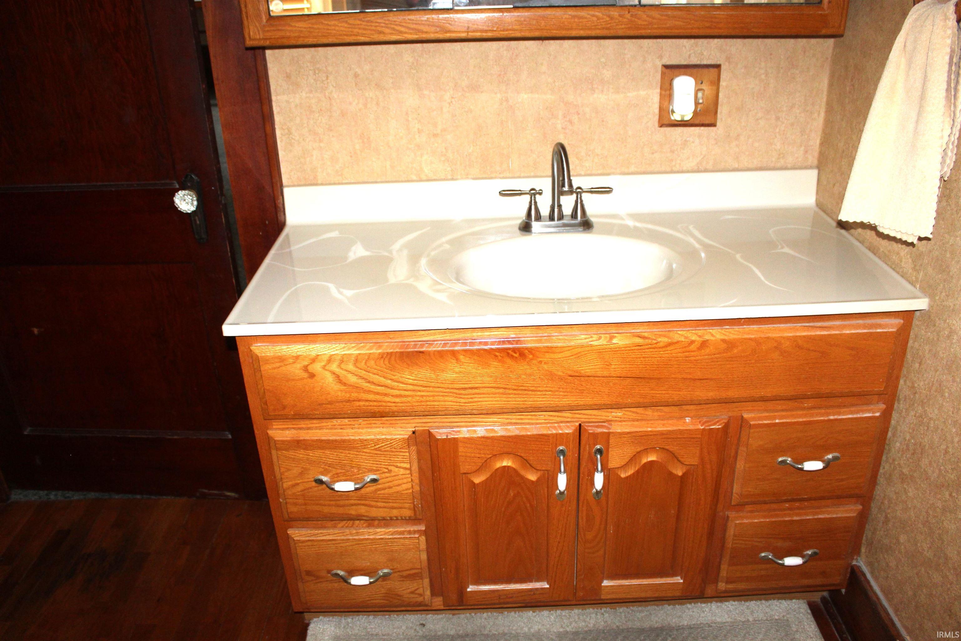 Wood-finish vanity with a light-toned countertop, integrated sink, and brushed nickel faucet