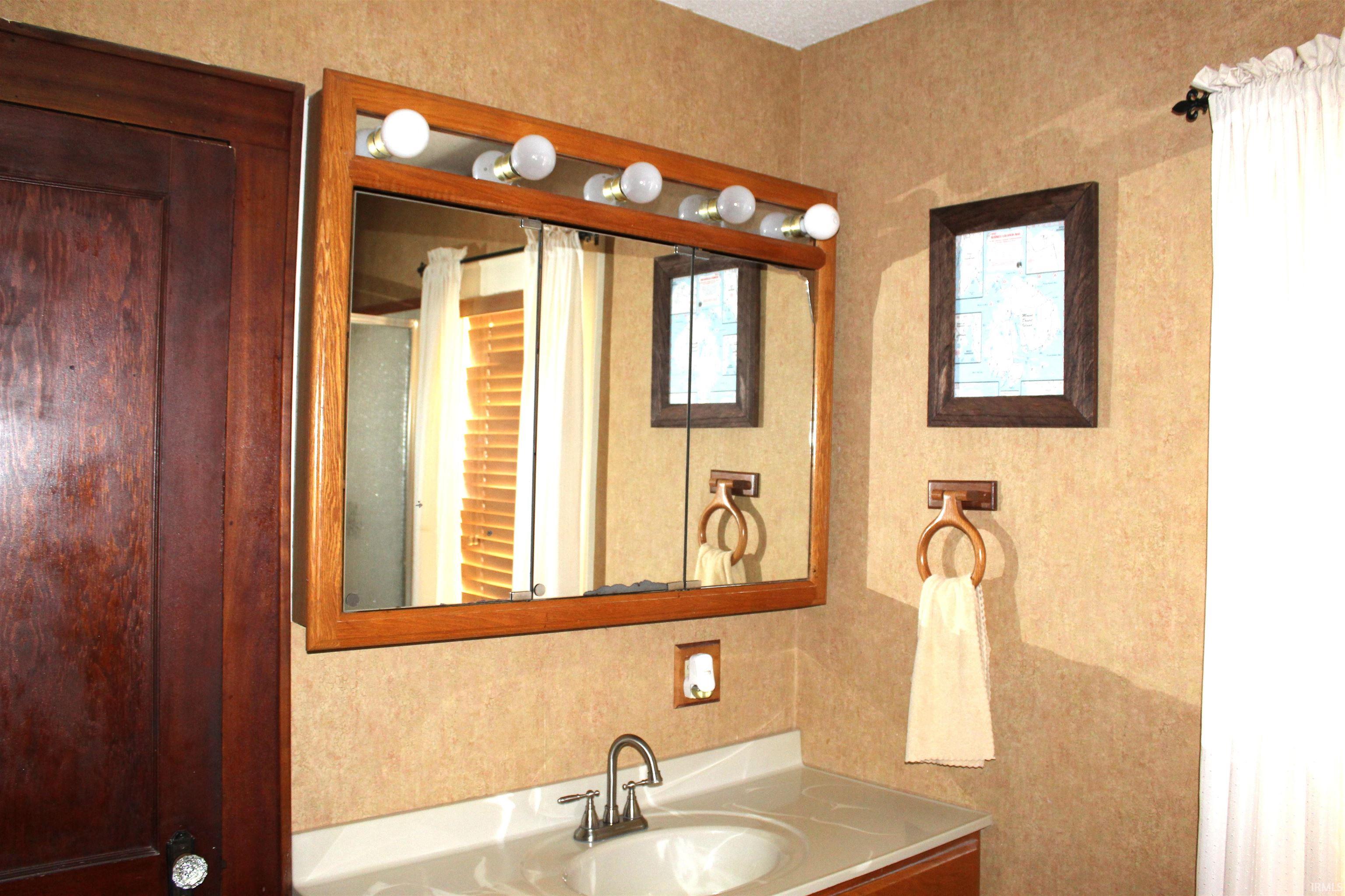Bathroom vanity featuring a light-colored countertop with an integrated sink and a brushed metal faucet