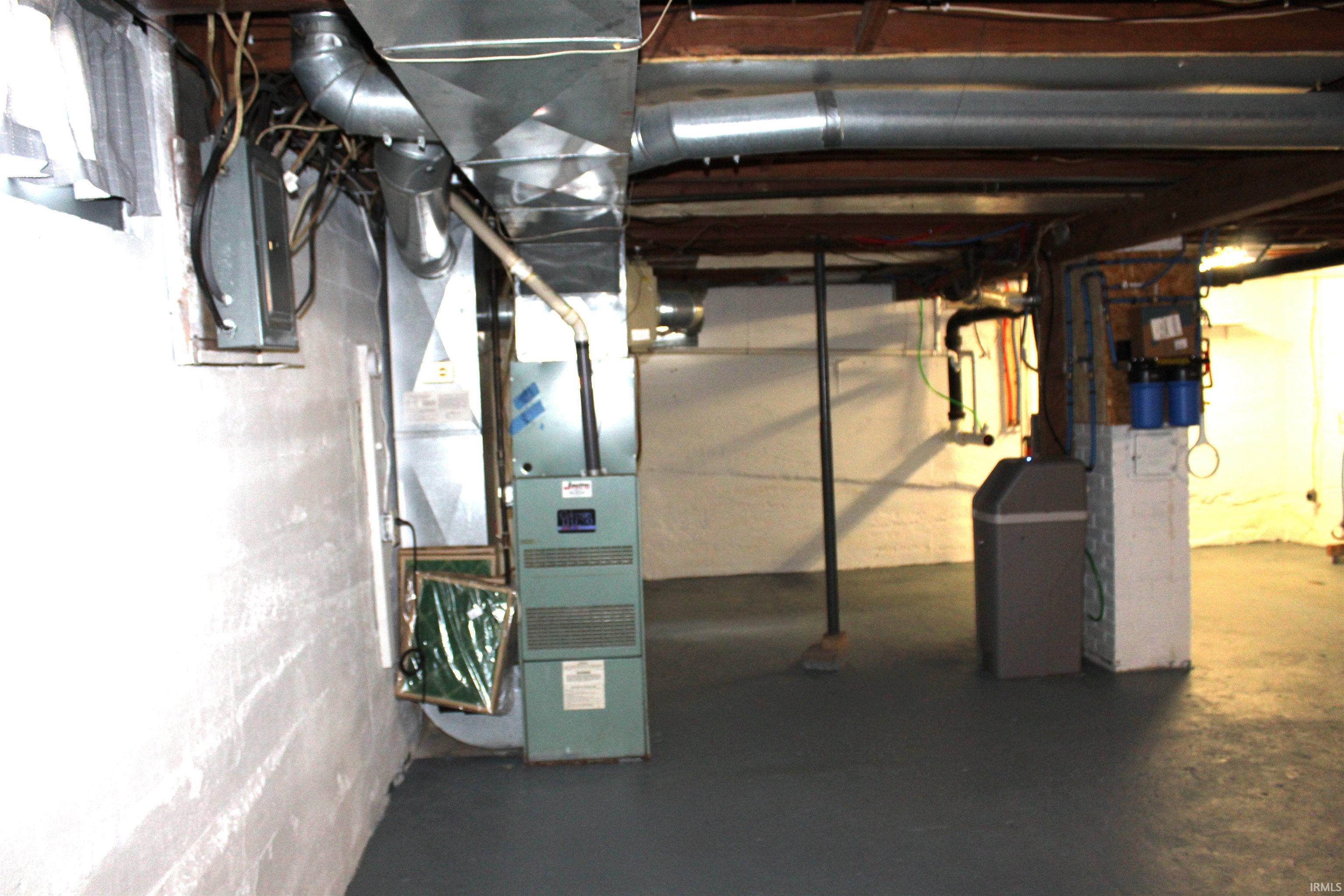 Utility area featuring a forced-air furnace, exposed ductwork, exposed ceiling joists, white painted concrete walls, and a gray painted concrete floor