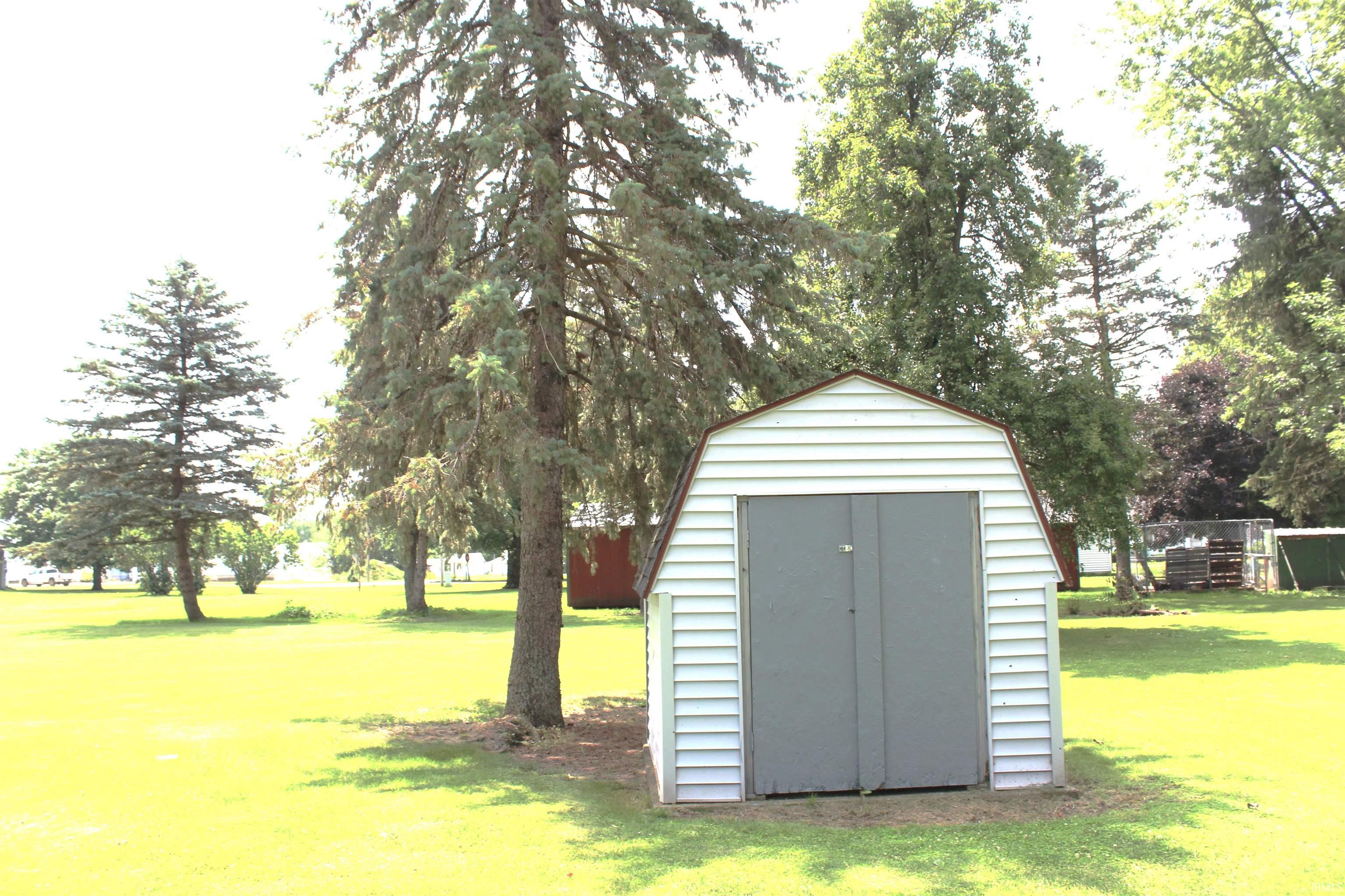 Freestanding storage shed with light-colored siding and a gambrel roof