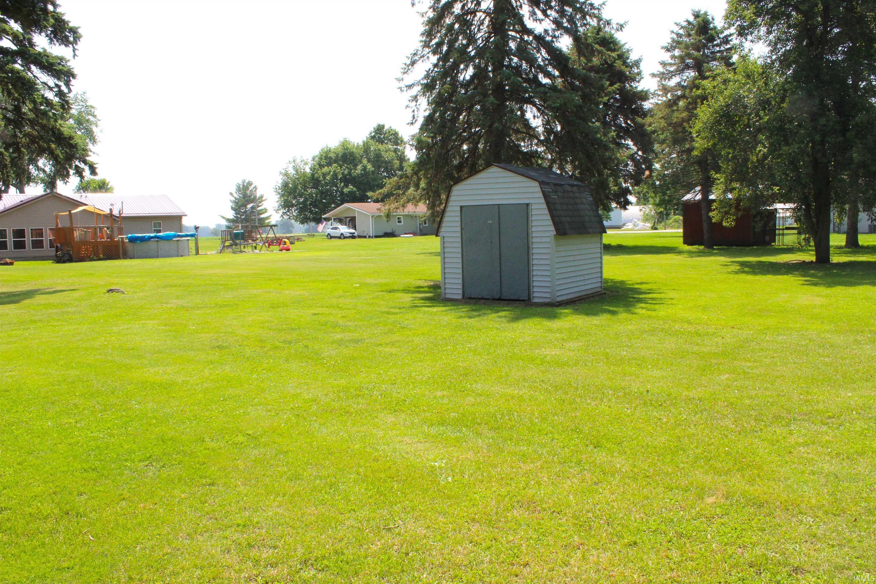 Expansive green lawn featuring a white storage shed with a gambrel roof and double gray doors