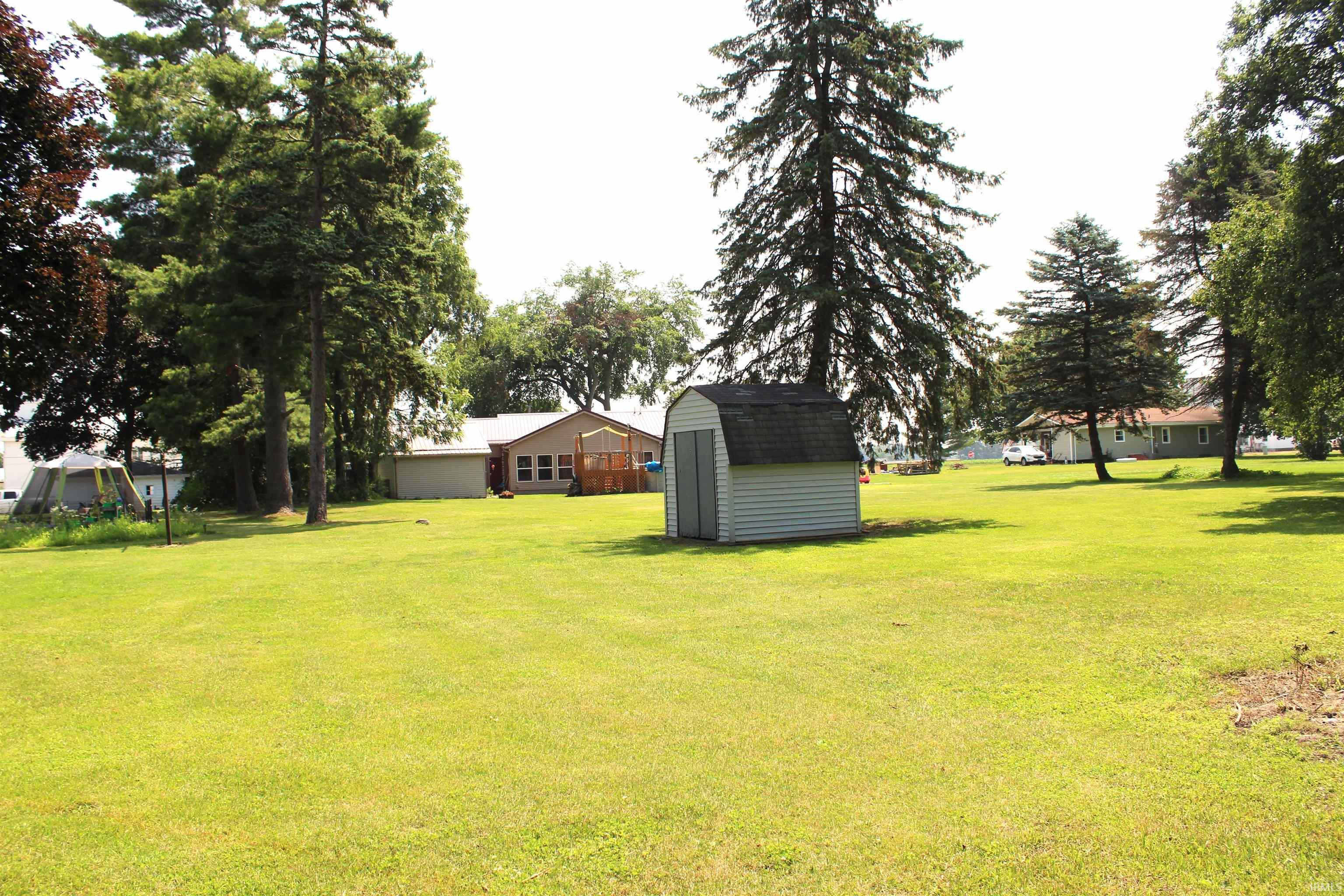 Expansive green lawn with mature trees and a detached shed