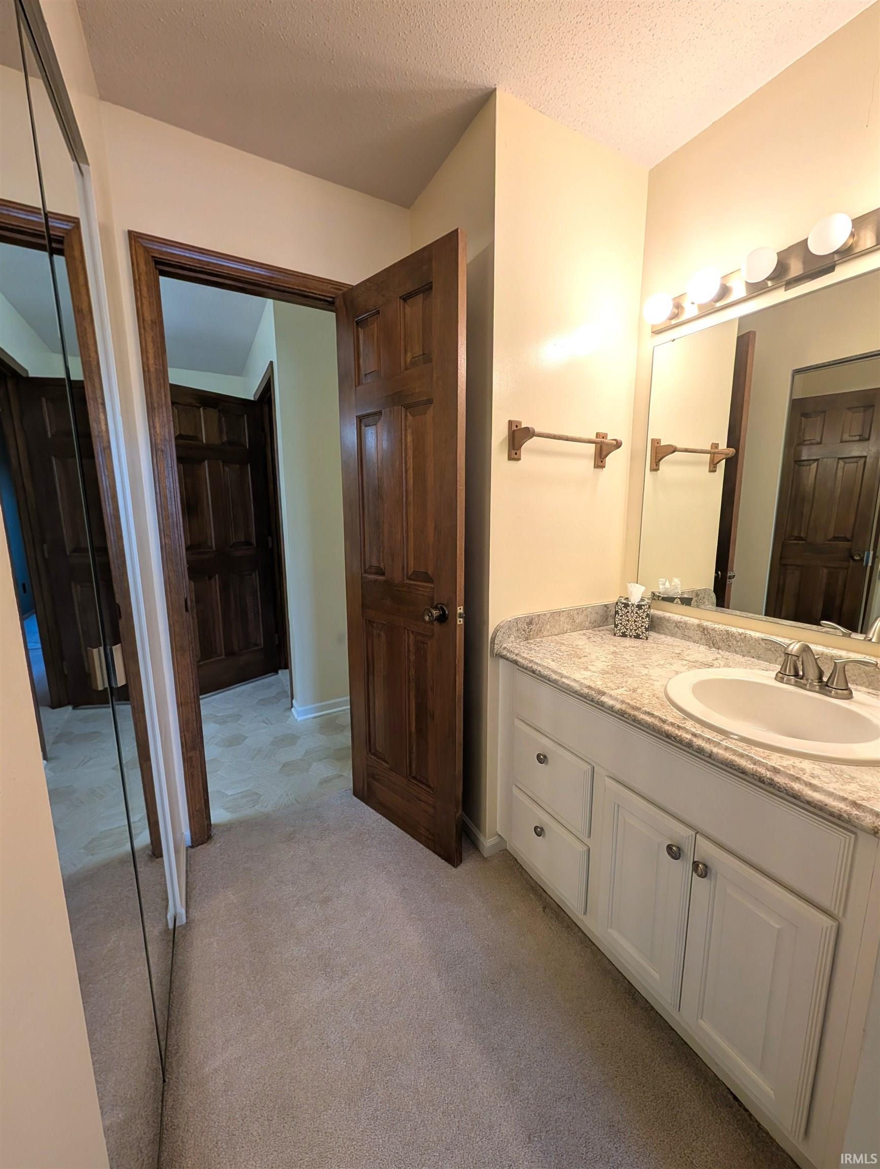 White vanity with a light-toned countertop, undermount sink, and polished chrome faucet