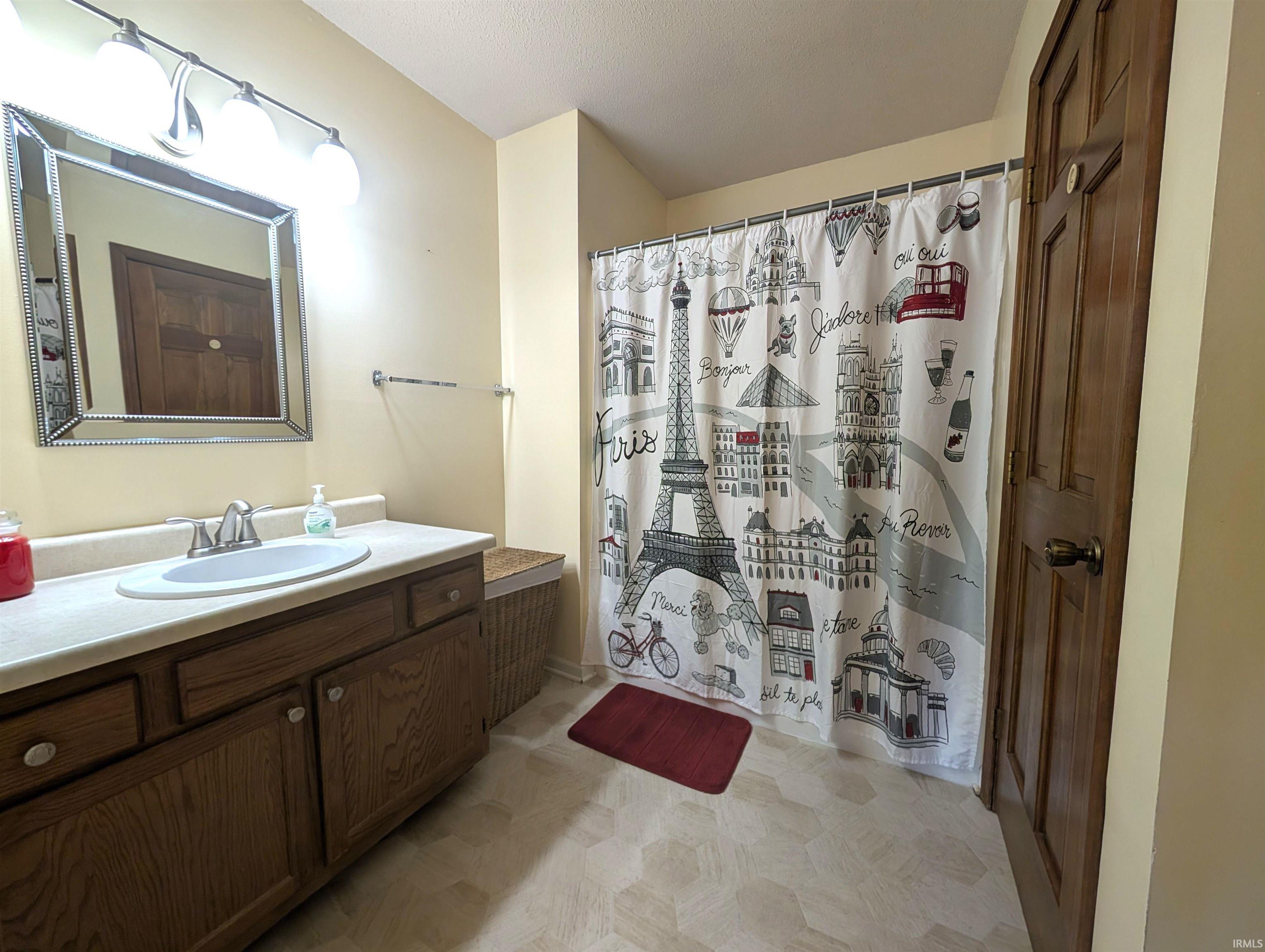 Bathroom featuring a single vanity with a white countertop, an undermount sink, and wood-finish cabinetry