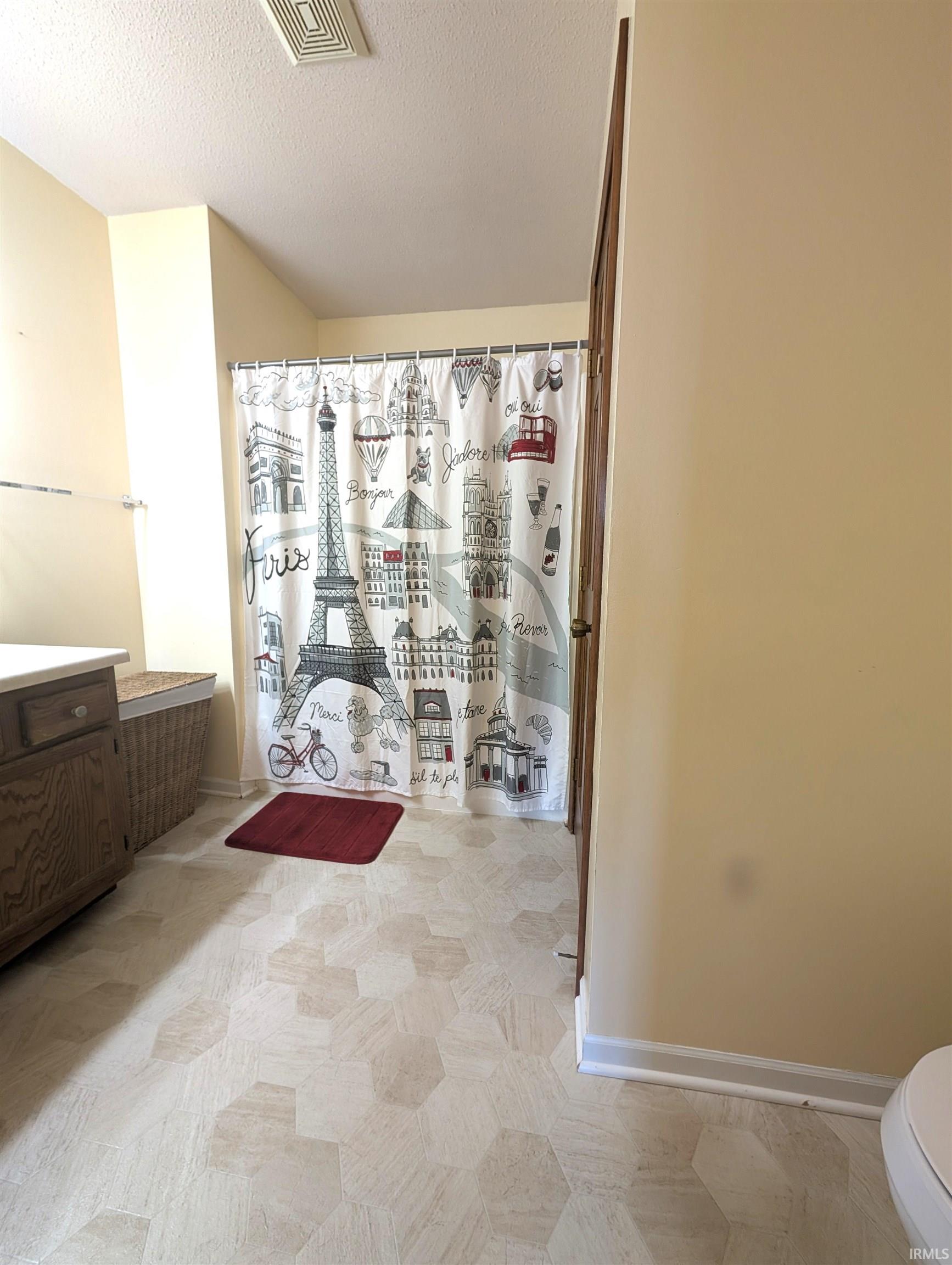 Bathroom featuring hexagonal pattern flooring, light-toned walls, and a built-in wood-finish vanity with a light-colored countertop