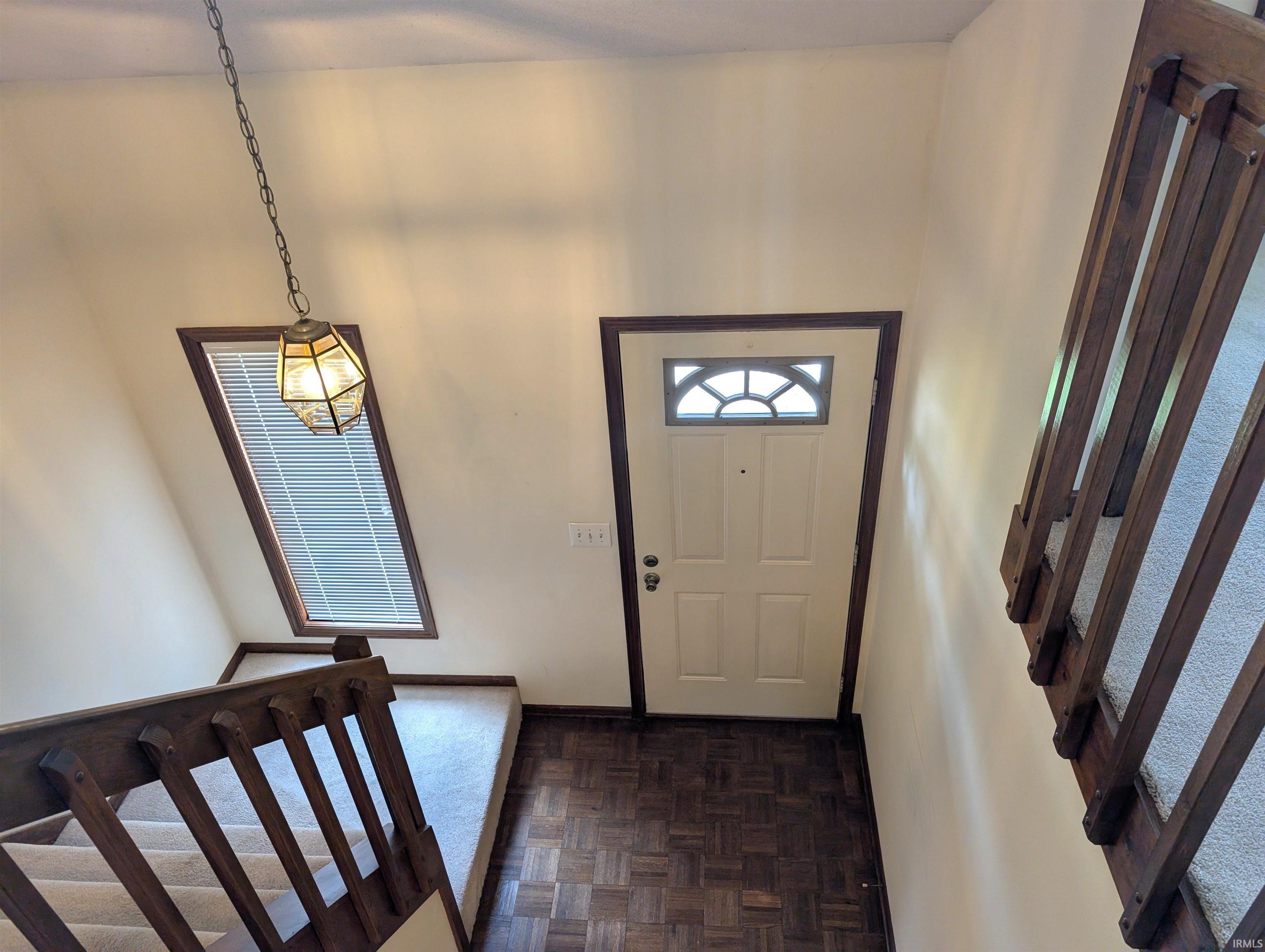 Foyer with parquet flooring and a white entry door featuring an arched transom window