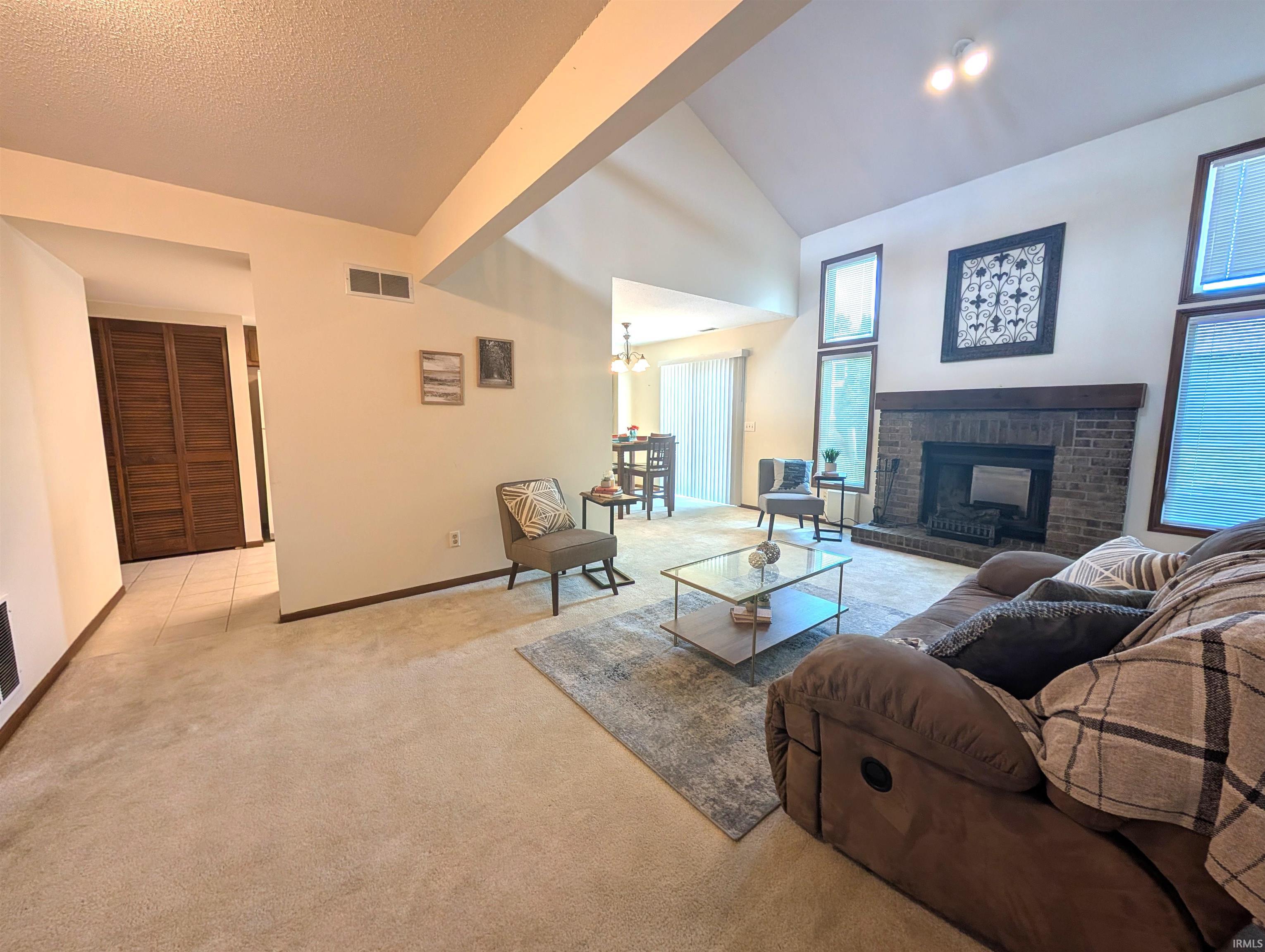 Spacious living area featuring a vaulted ceiling and a brick fireplace