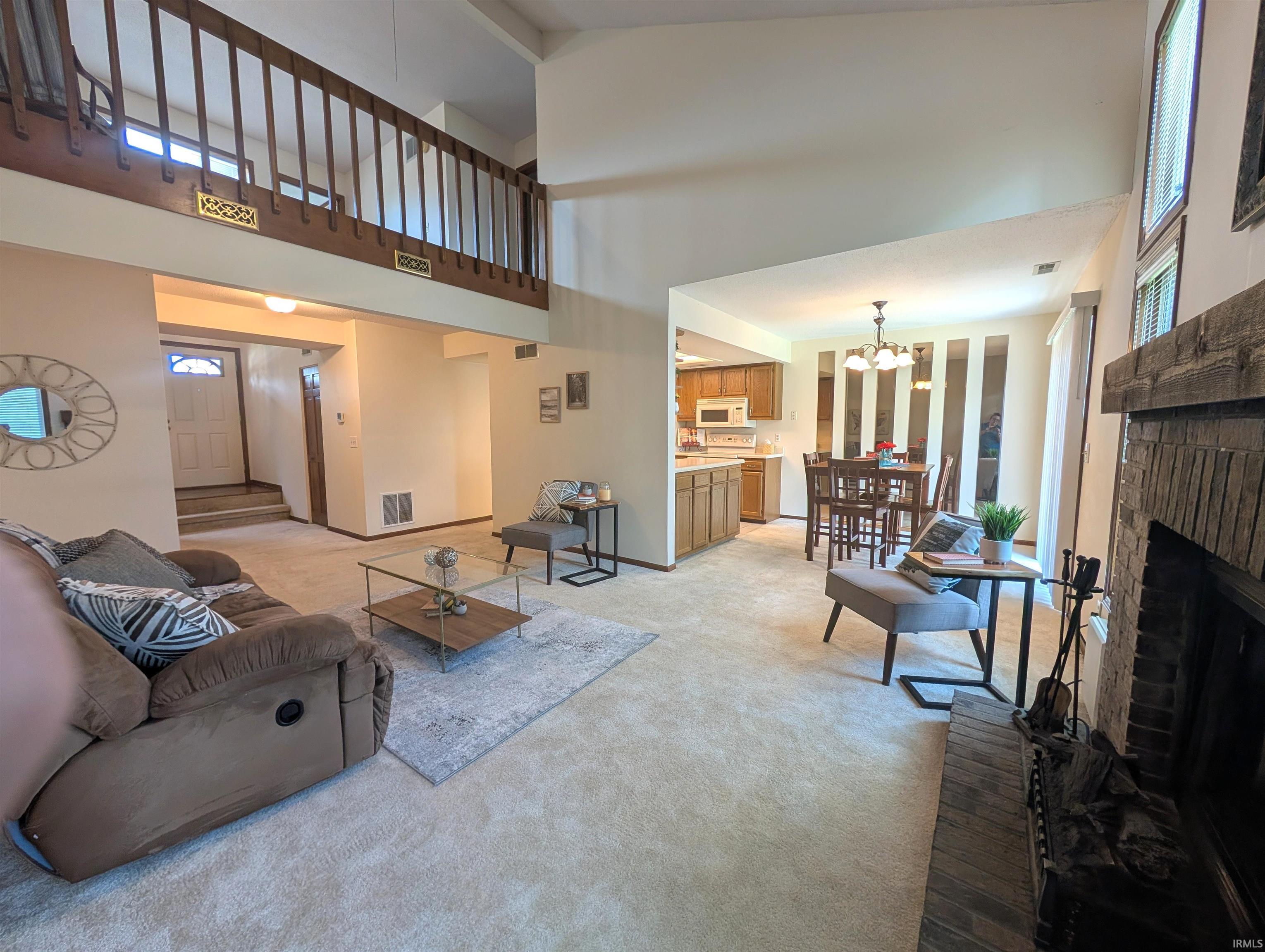 Spacious living room featuring a vaulted ceiling and a brick fireplace