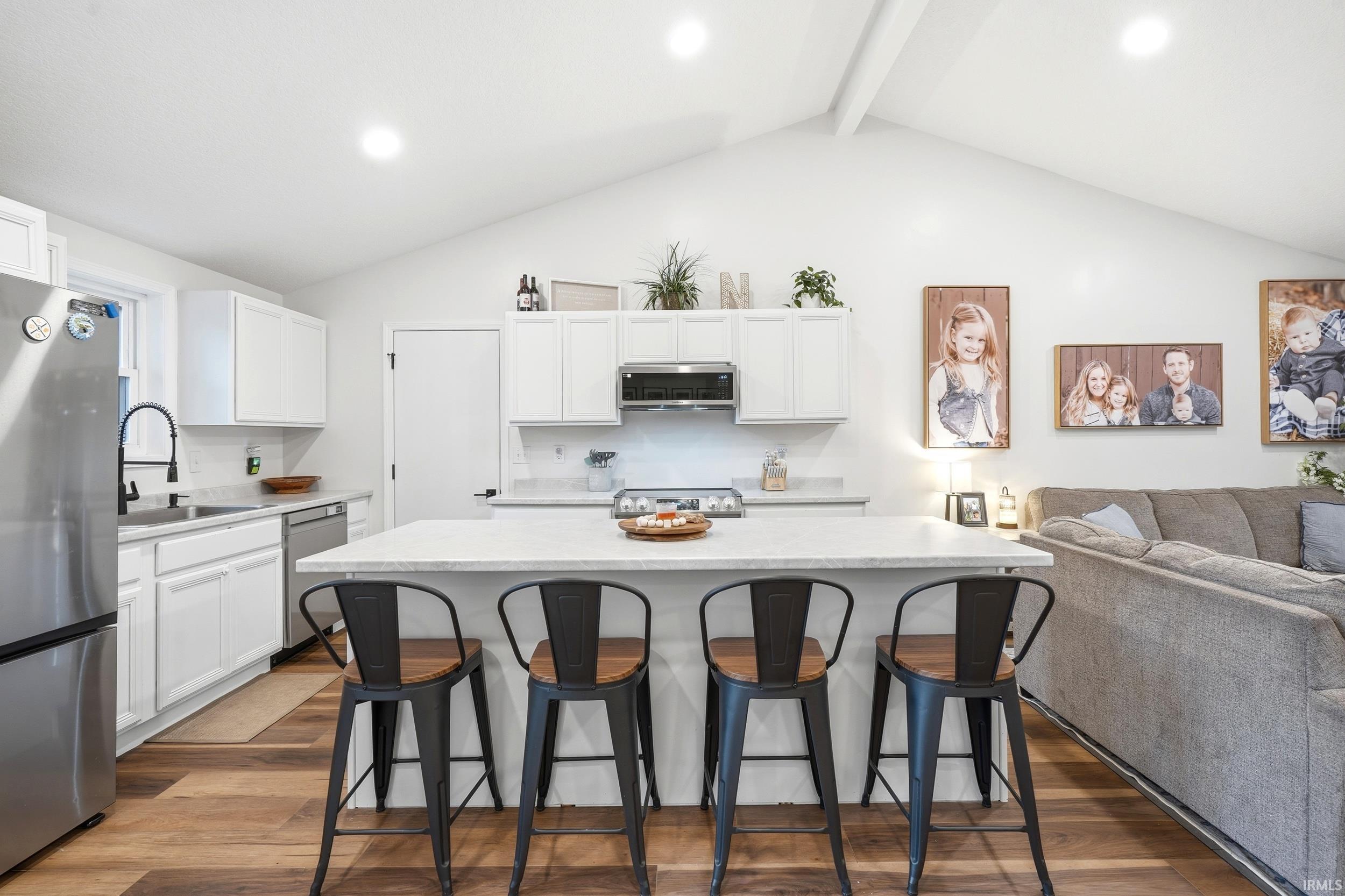 Open-concept living area featuring a vaulted ceiling and wood-finish flooring