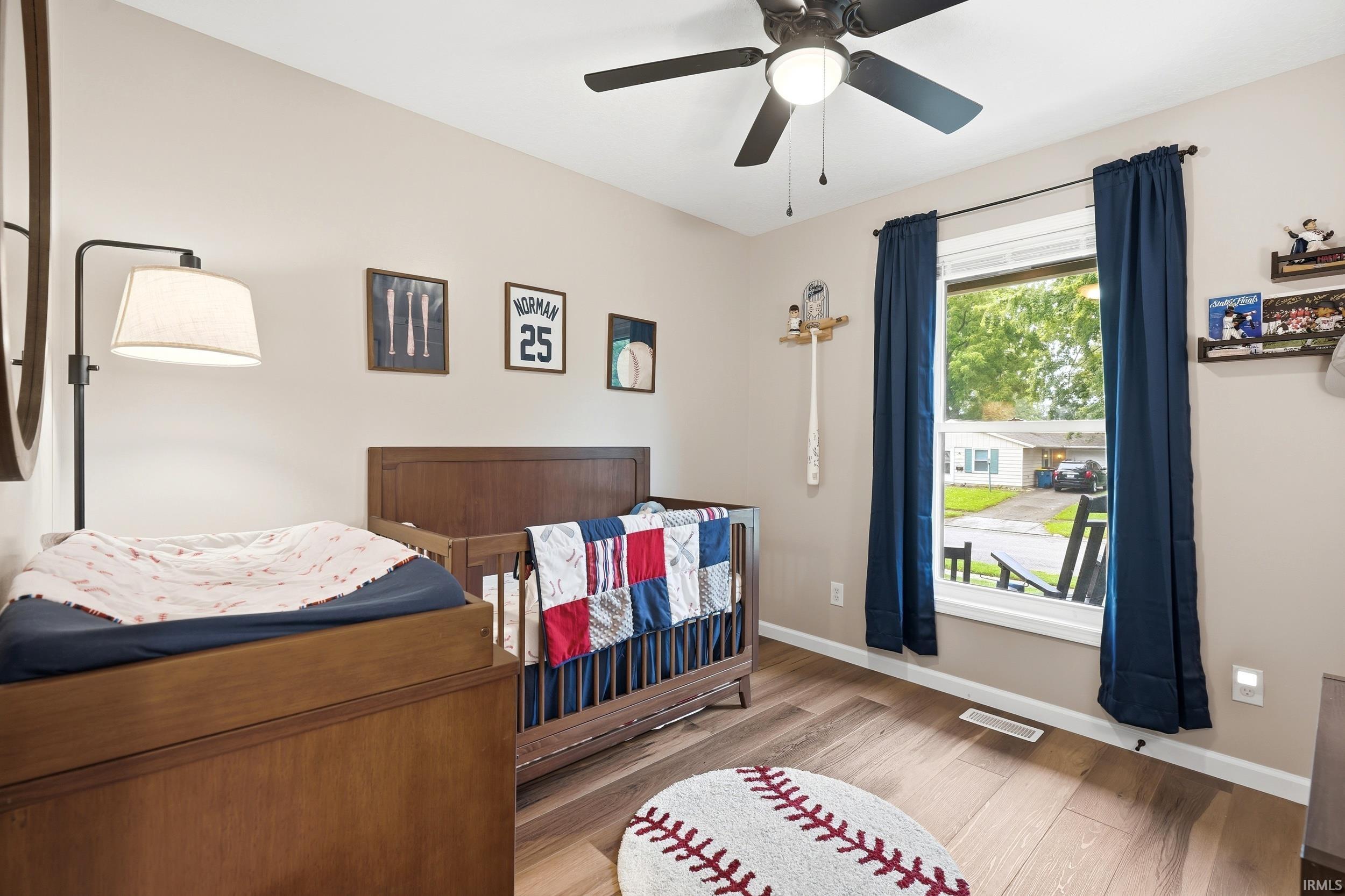 Light-filled room featuring wood-finish flooring and a ceiling fan with integrated lighting