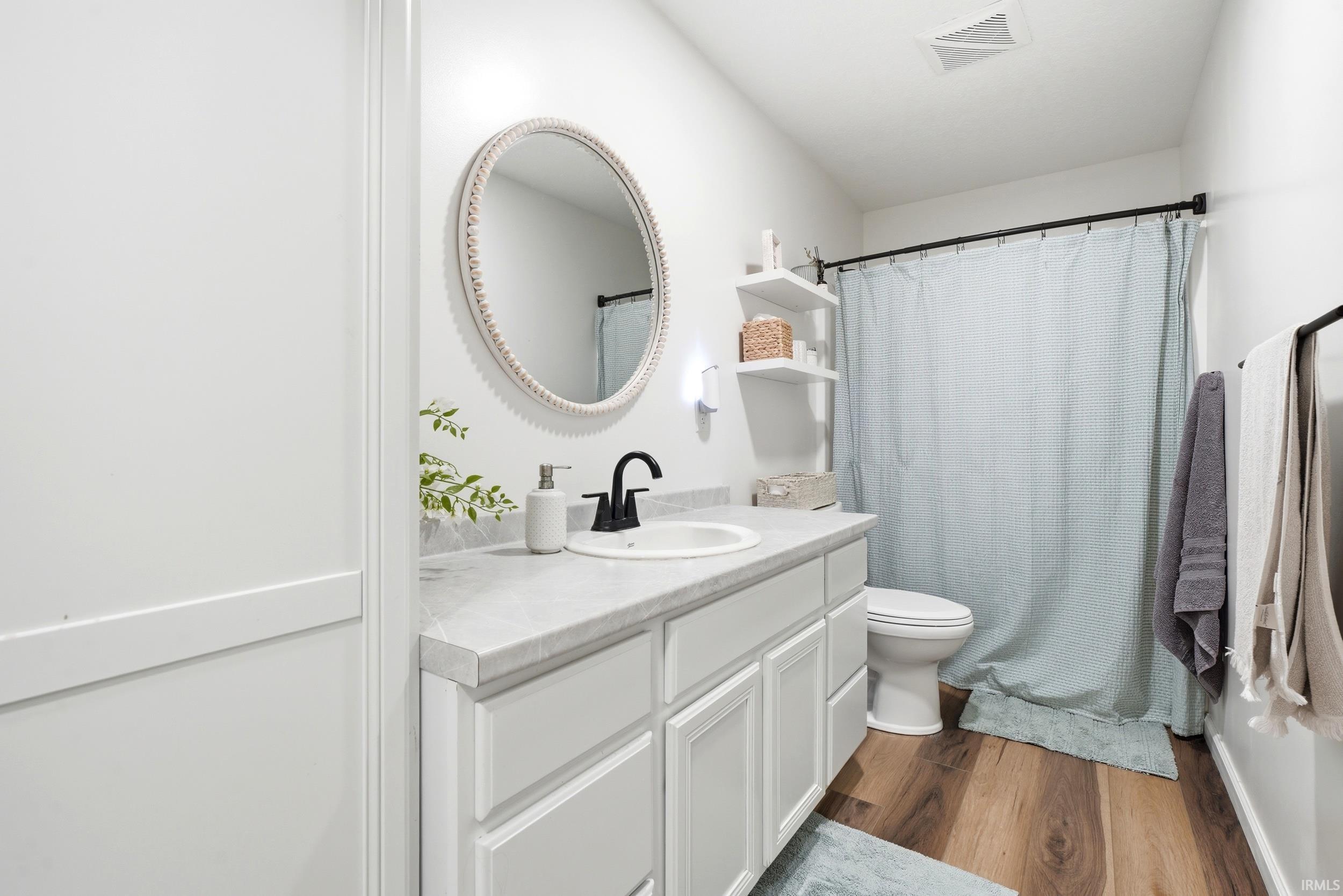 Bathroom featuring a white vanity with paneling, a light-toned countertop, and an undermount sink with a matte black faucet