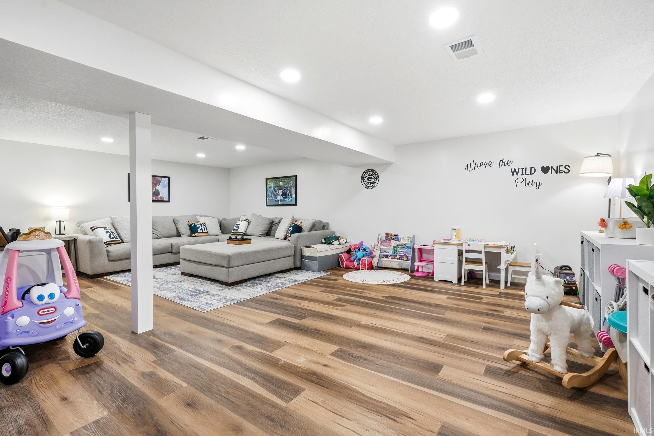 Spacious lower-level area with wood-finish flooring, recessed lighting, and bright white walls