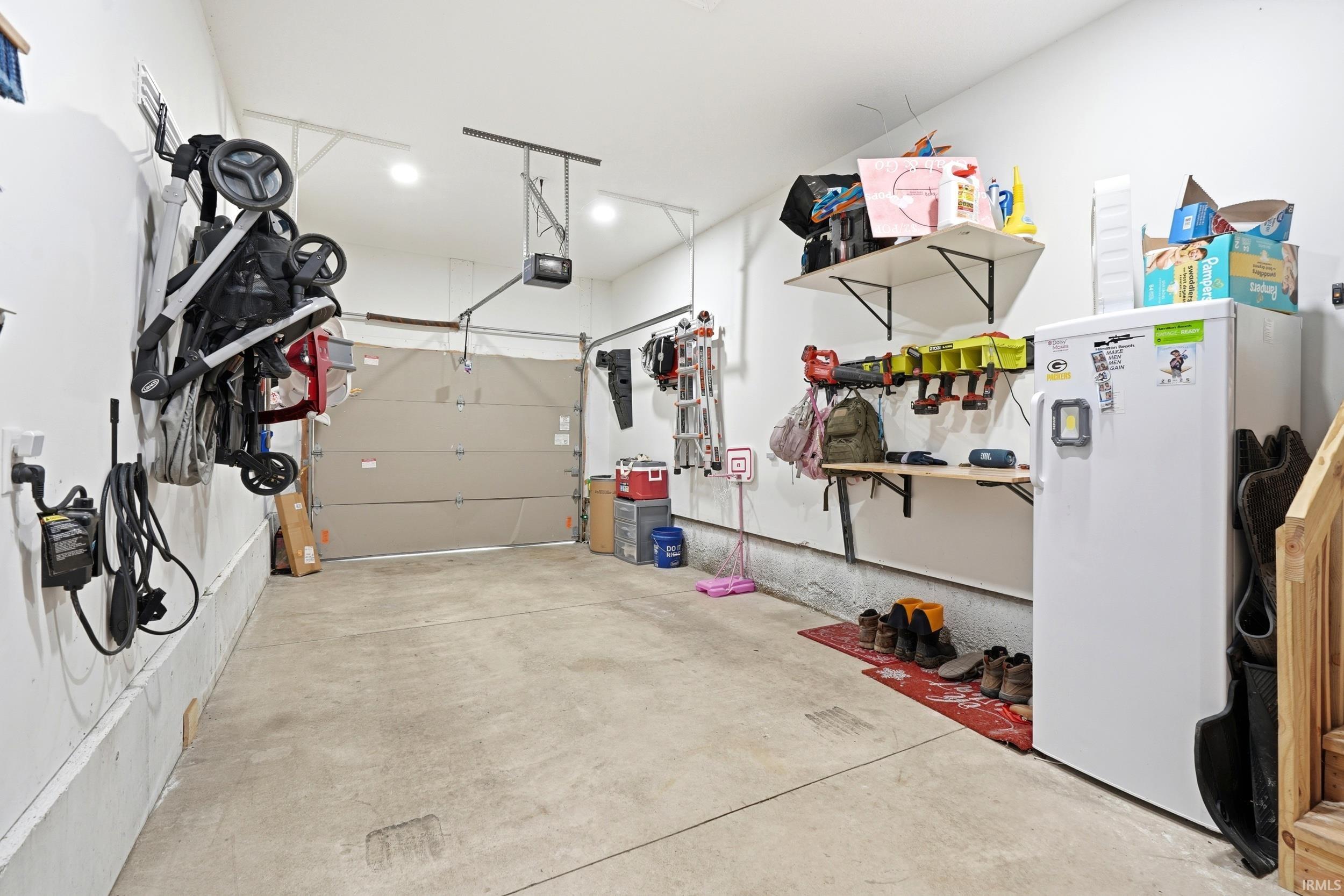 Spacious garage featuring a concrete floor, overhead lighting, and a neutral-toned garage door