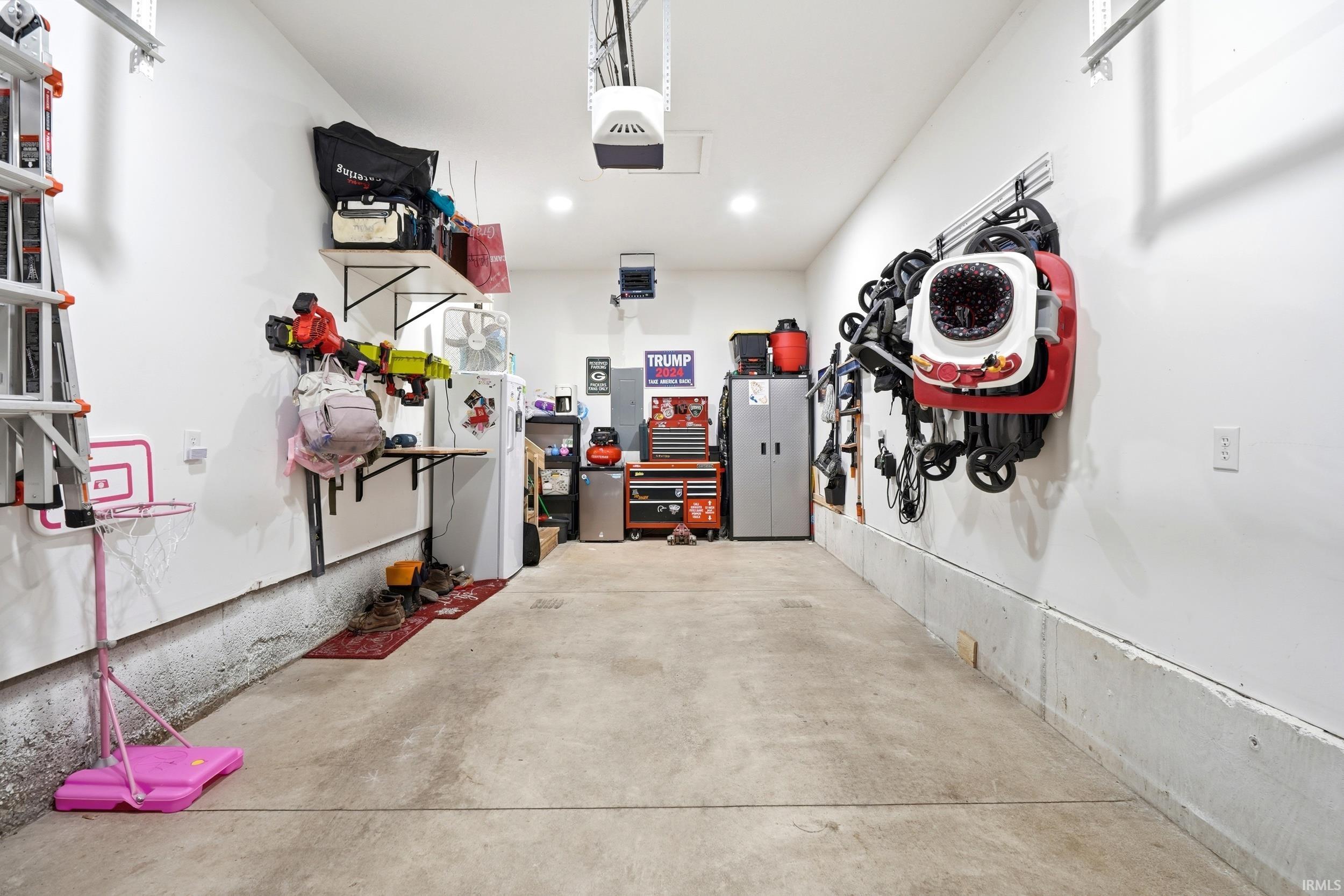 Spacious garage with concrete flooring, overhead lighting, and white finished walls