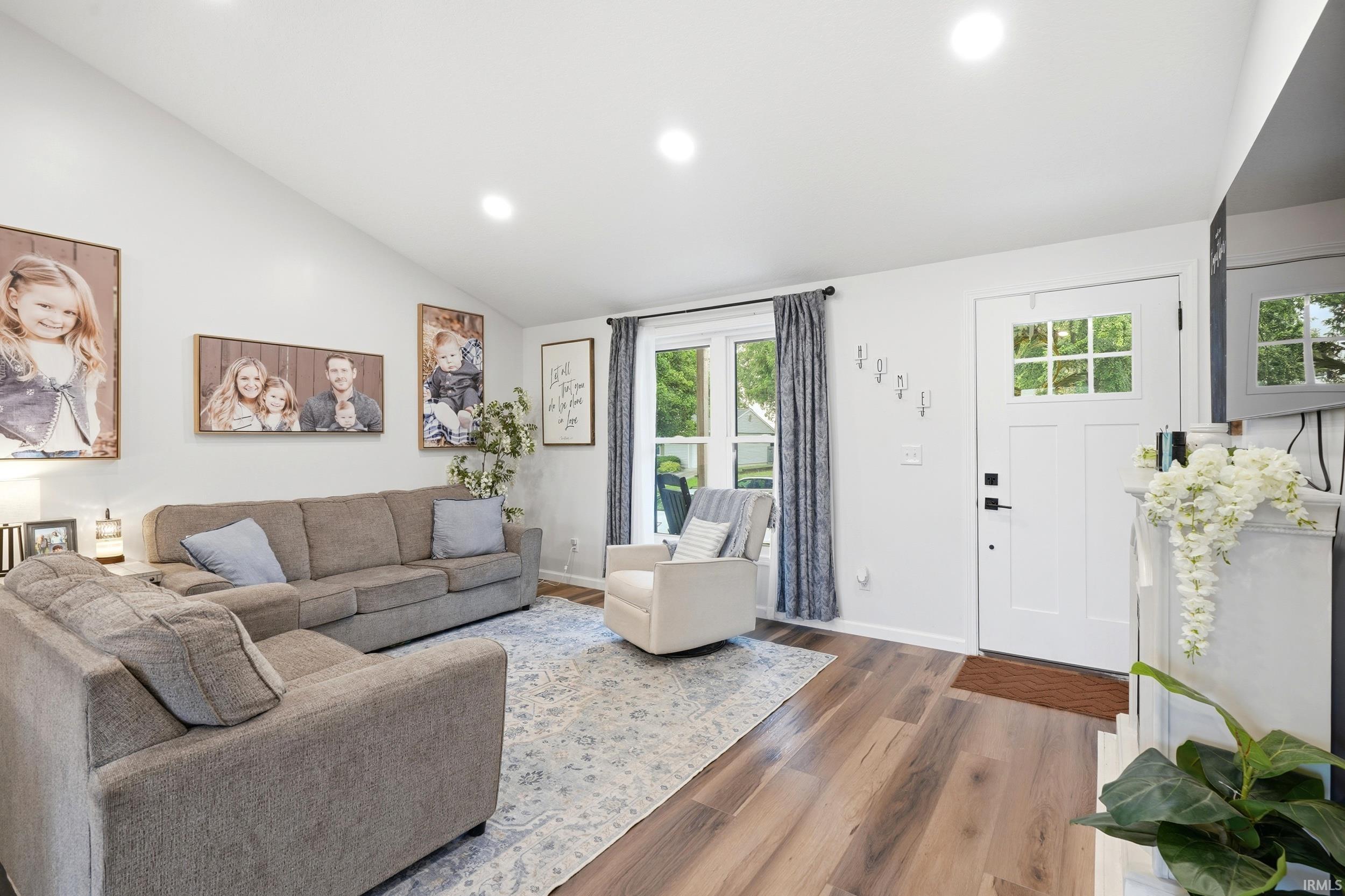 Inviting living space featuring wood-finish flooring, recessed lighting, and a vaulted ceiling