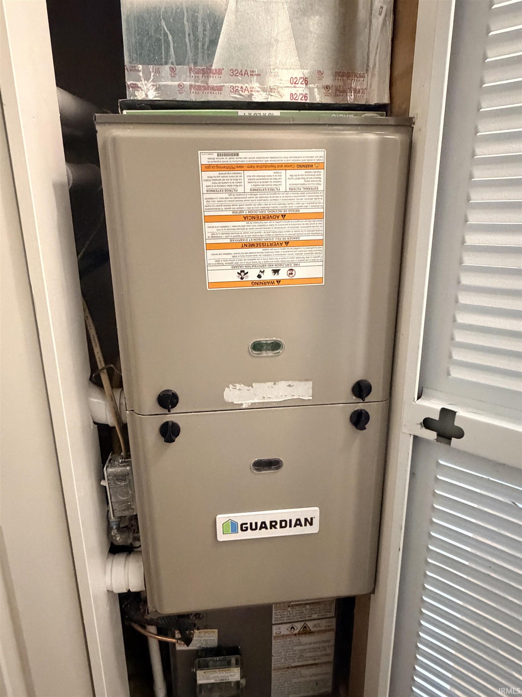 HVAC system with metal ductwork, concealed within a utility closet featuring a louvered bifold door