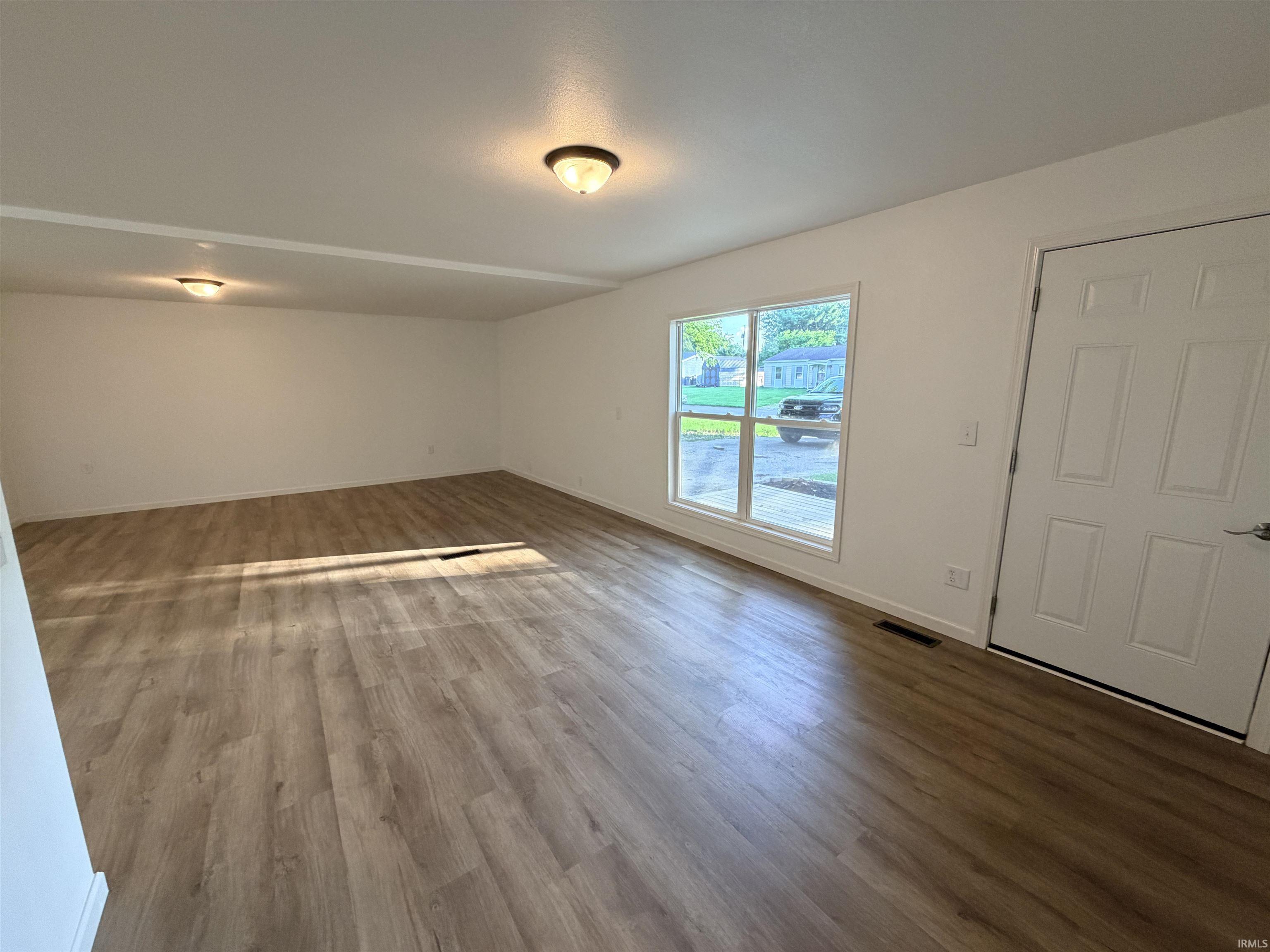 Spacious interior featuring wood-finish flooring, white walls, and flush-mount lighting fixtures