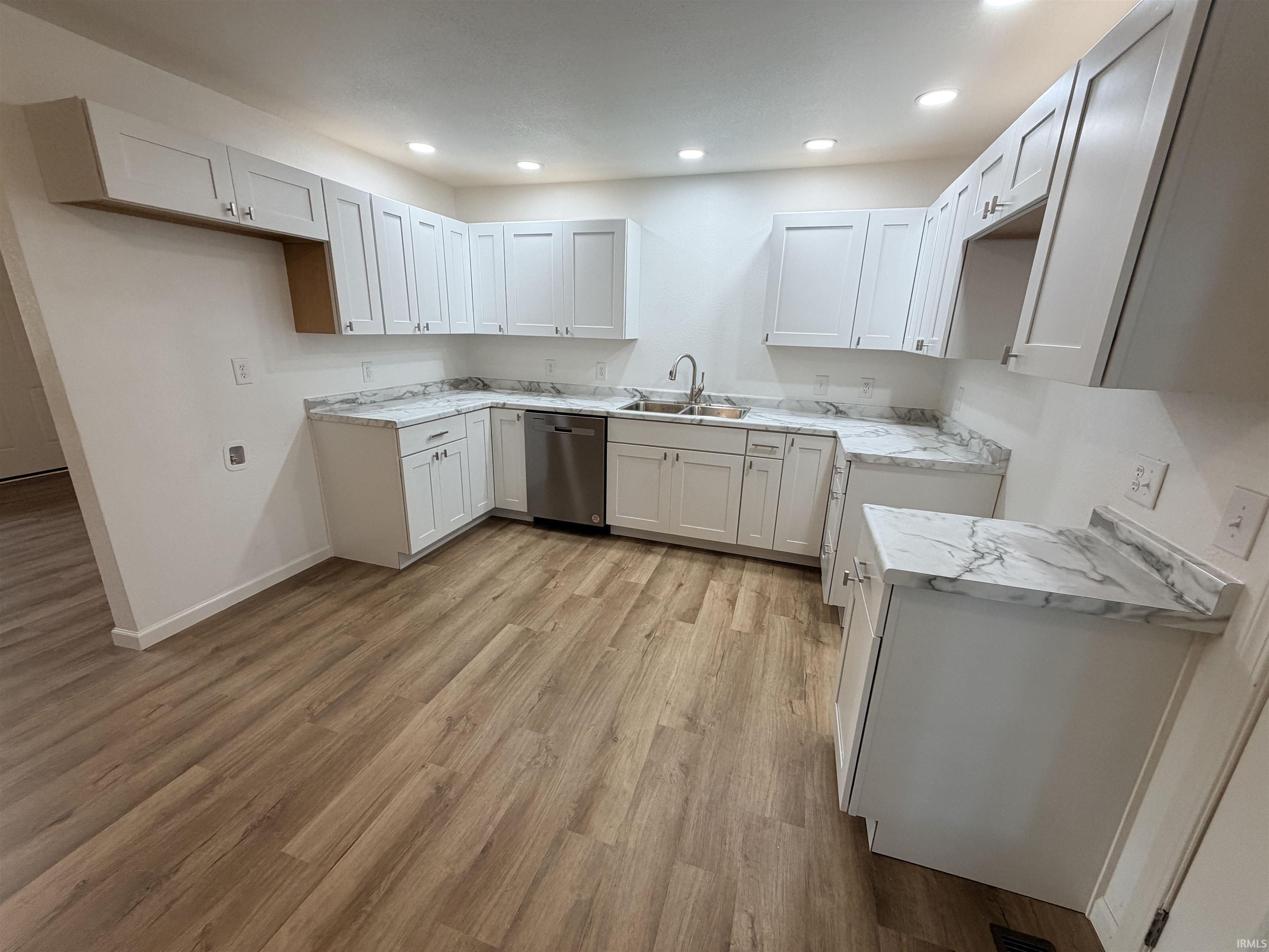 Kitchen featuring white shaker-style cabinetry, stainless steel dishwasher, wood-finish flooring, recessed lighting, and patterned countertops