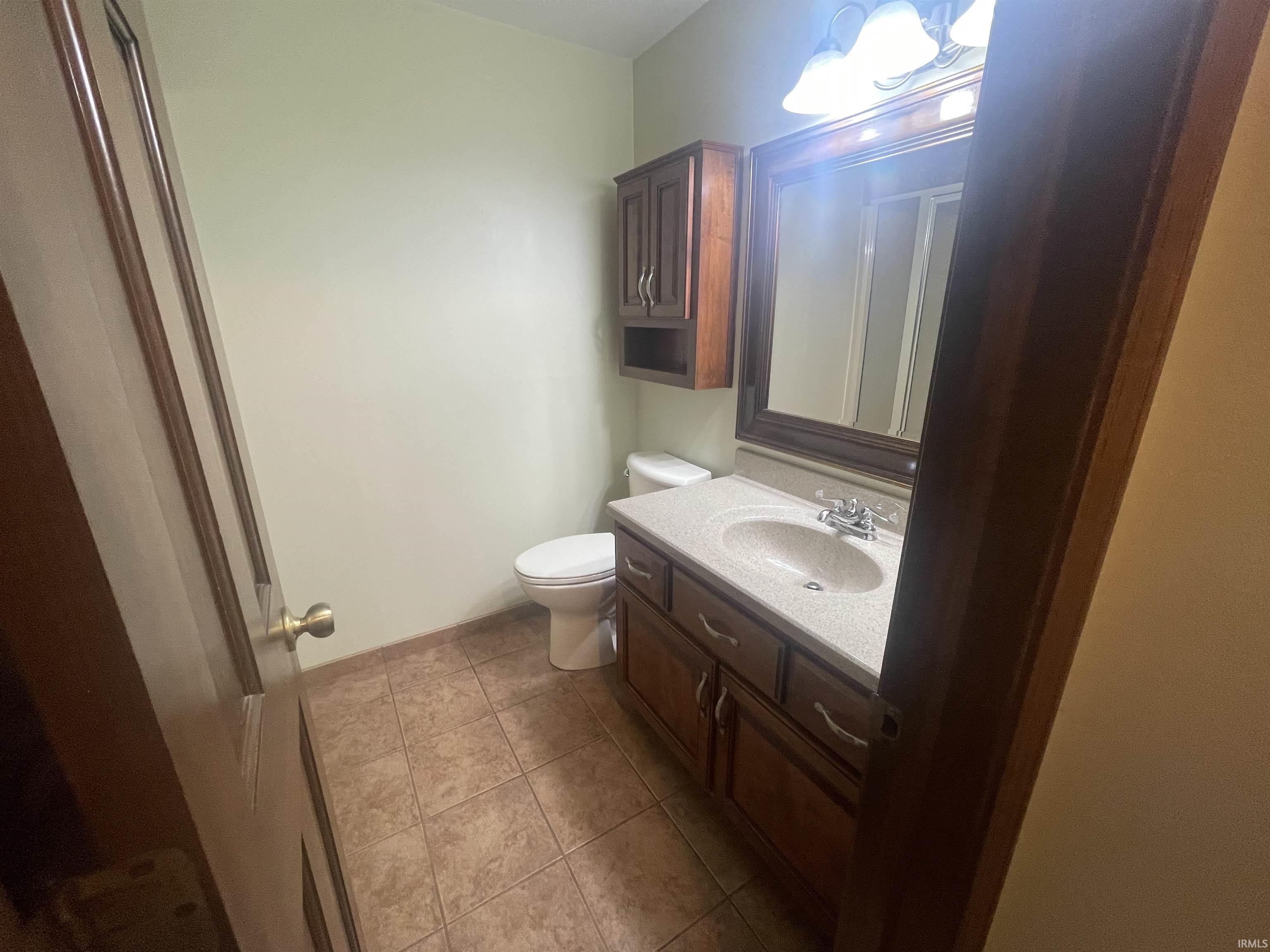 Bathroom featuring a wood-finish vanity with an integrated sink and light-toned countertop