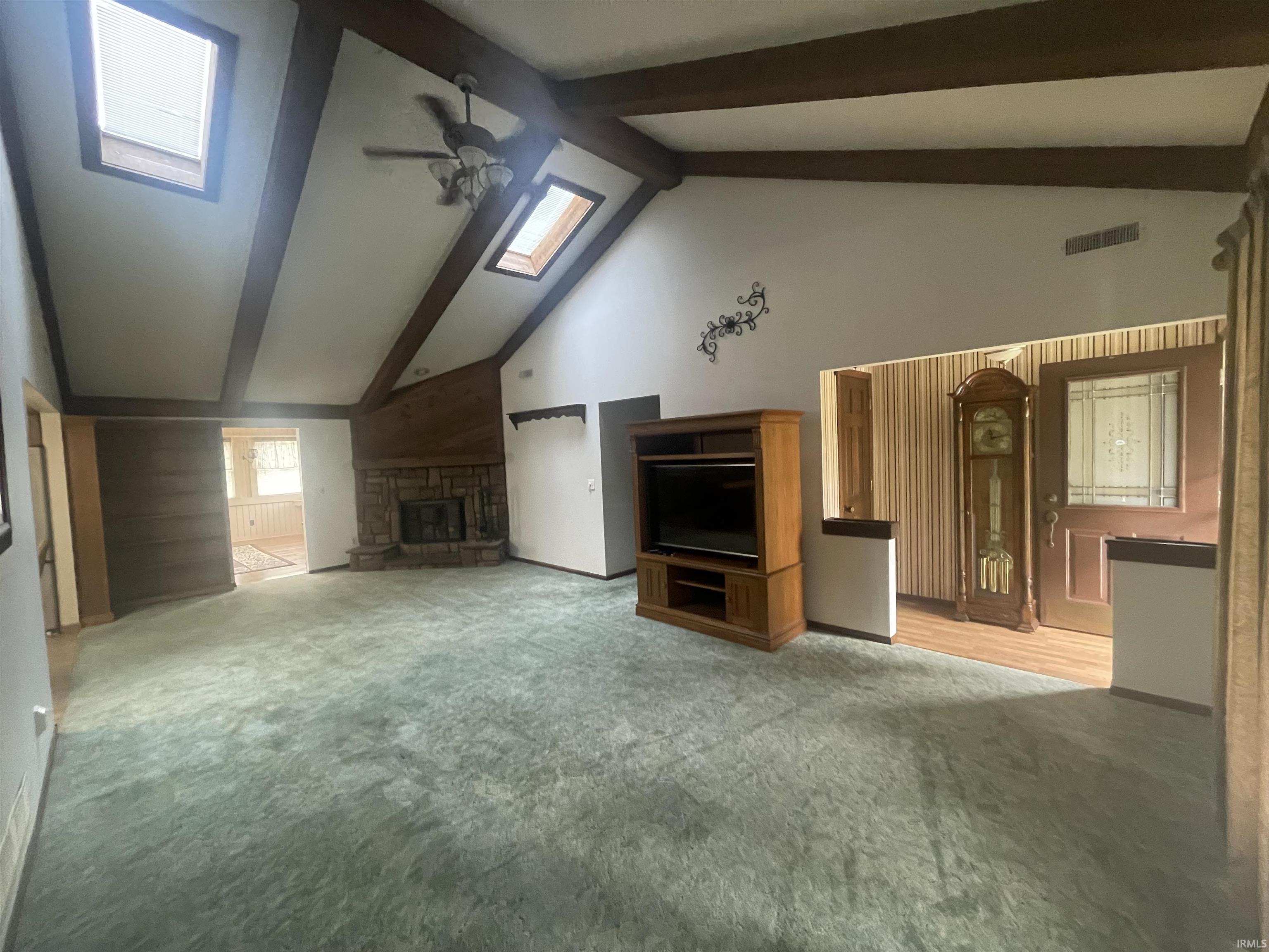Vaulted ceiling featuring exposed wood beams and two skylights