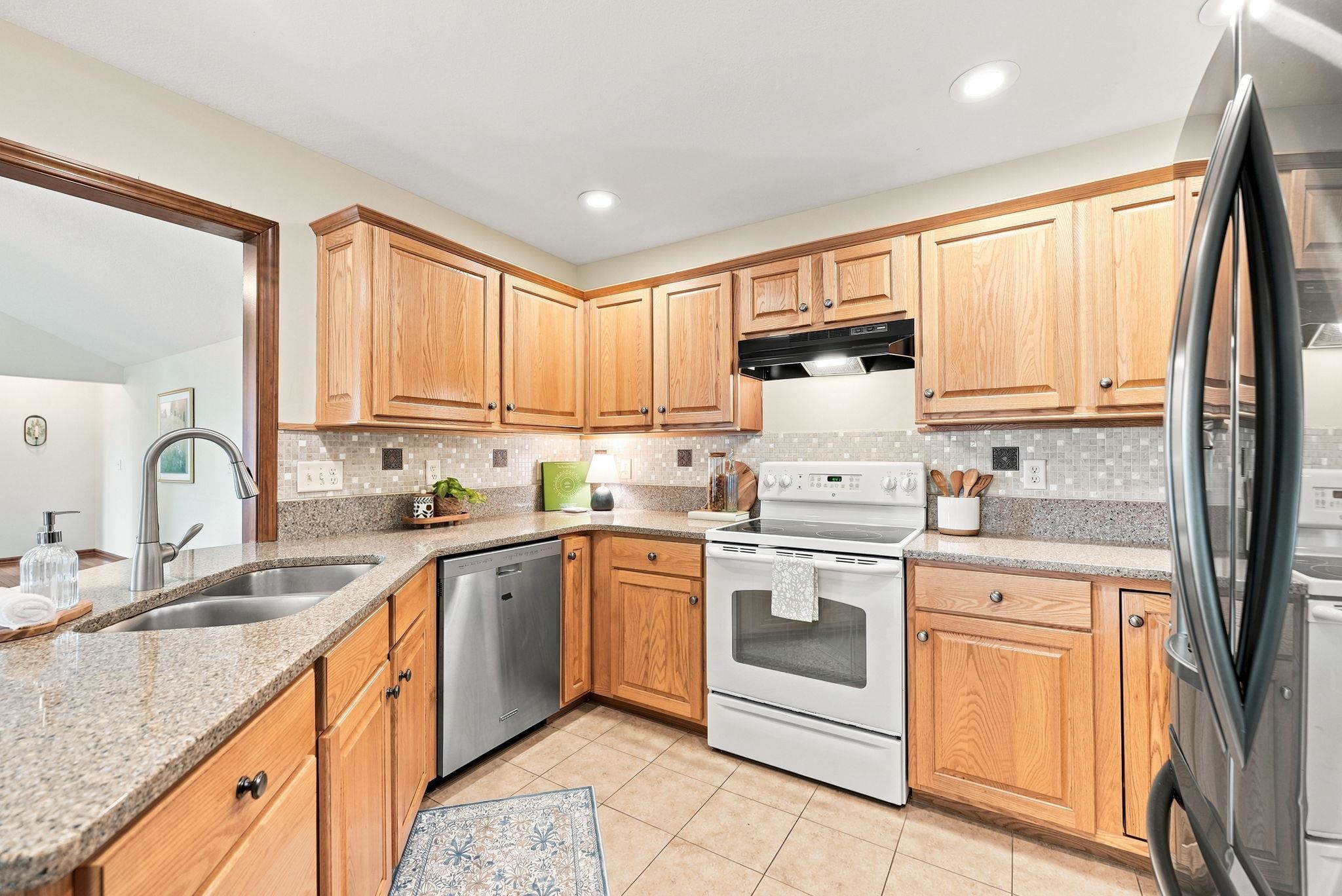 Kitchen featuring light wood cabinetry, granite countertops, and a mosaic tile backsplash