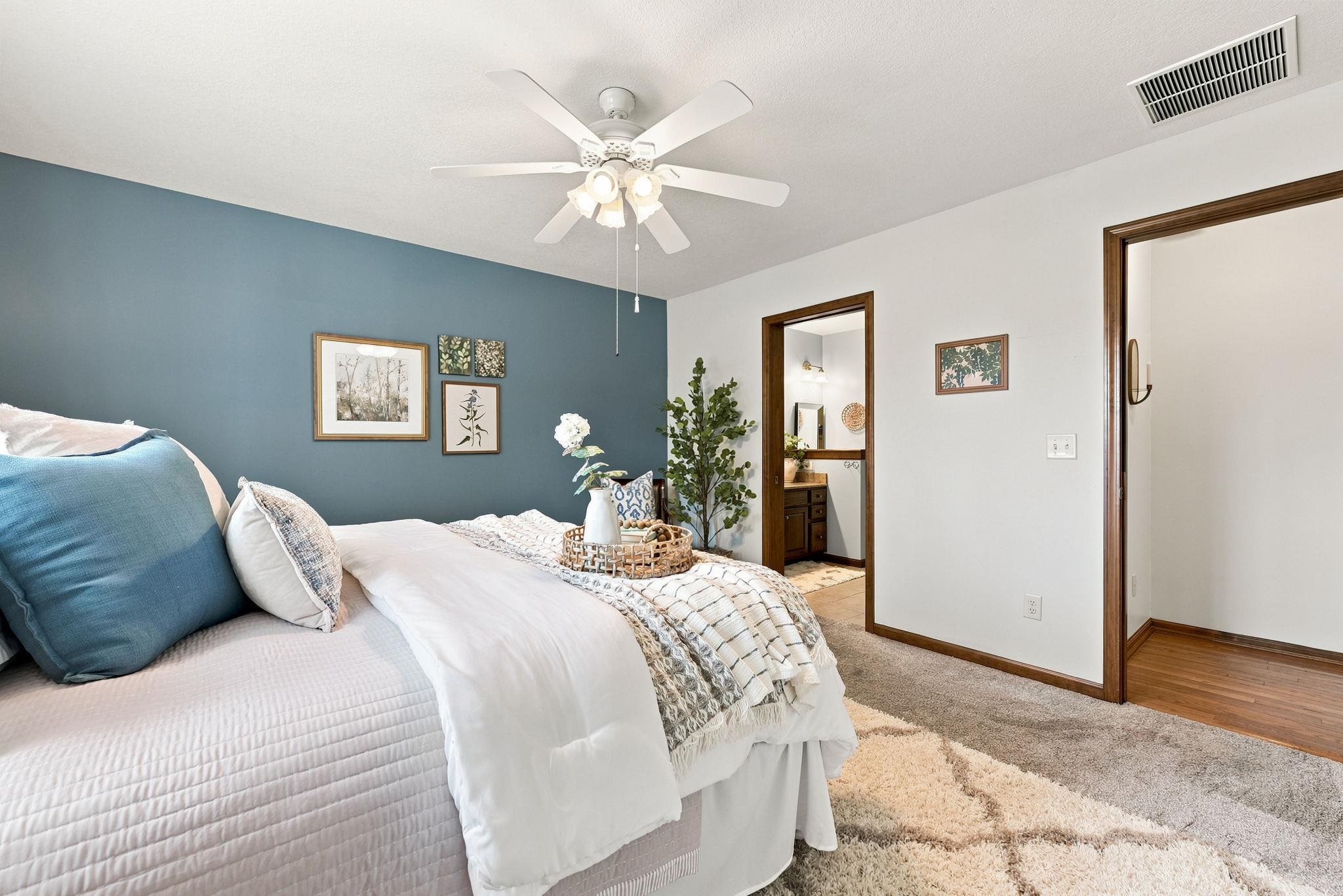 Bedroom featuring a blue accent wall and neutral carpeting