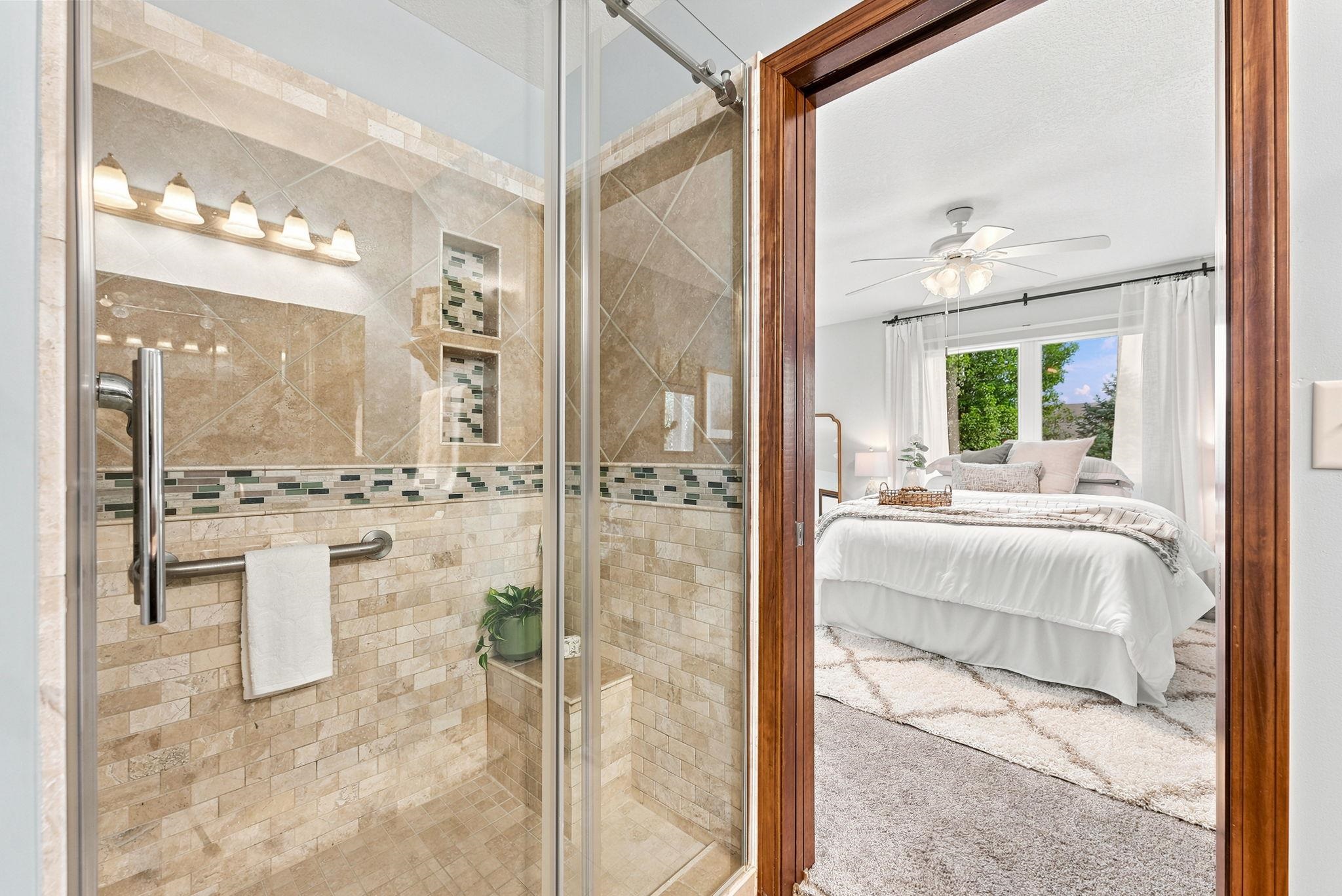 Tiled walk-in shower featuring a built-in bench, glass enclosure, recessed shelving, and a decorative tile accent band