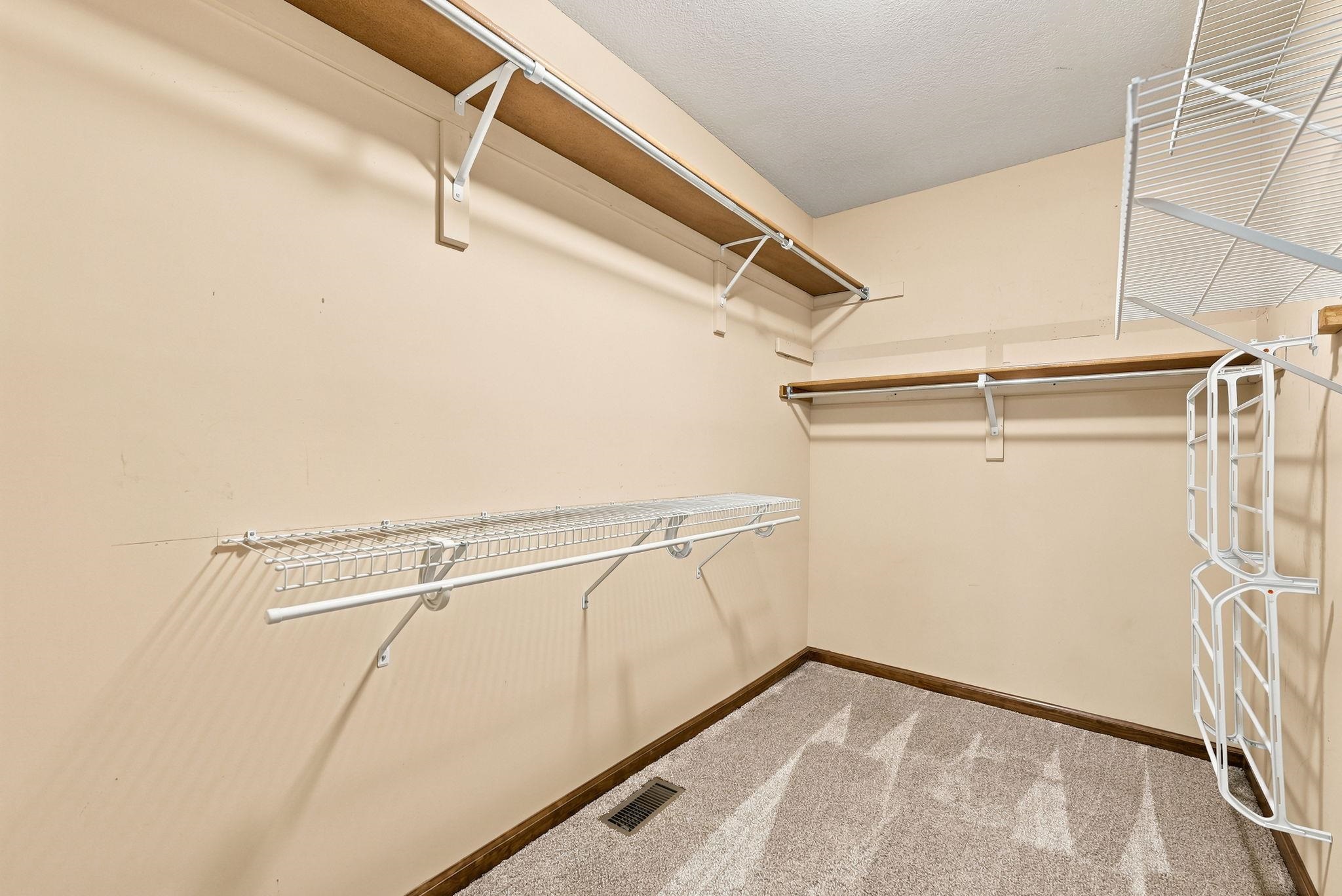 Walk-in closet featuring light beige walls and a patterned carpet