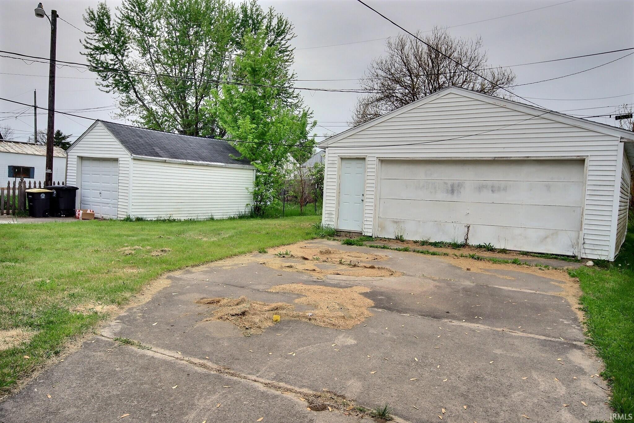 Two detached garages featuring white siding and asphalt shingle roofing