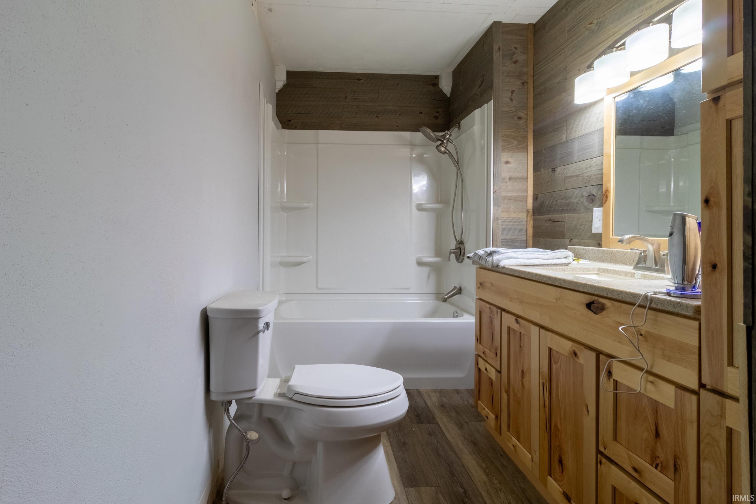 Bathroom featuring a full vanity with light wood cabinetry, a light-colored countertop, and a mirror with overhead lighting