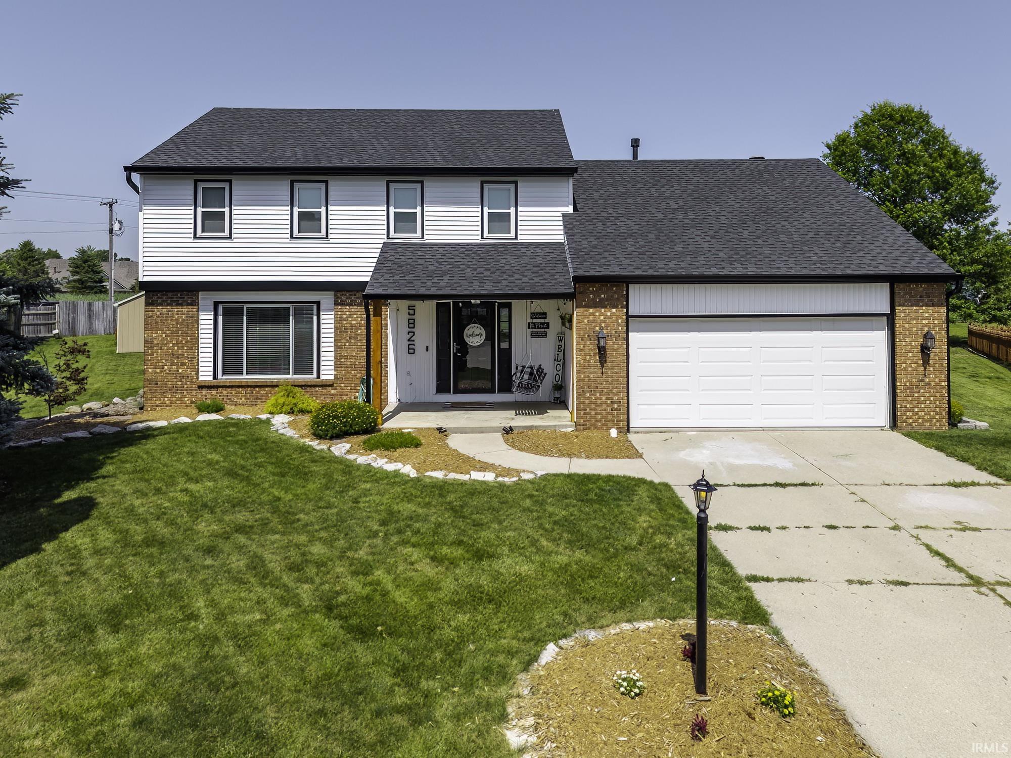Two-story residence featuring a brick and white siding exterior, dark shingle roof, and an attached two-car garage
