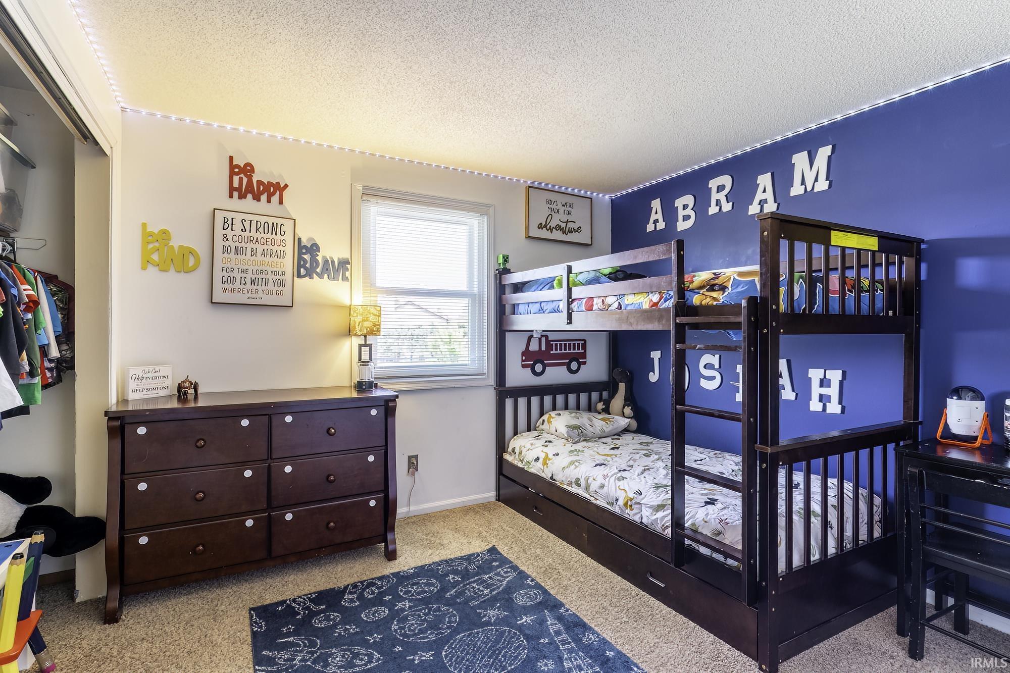 Room featuring textured carpeting and a window with blinds