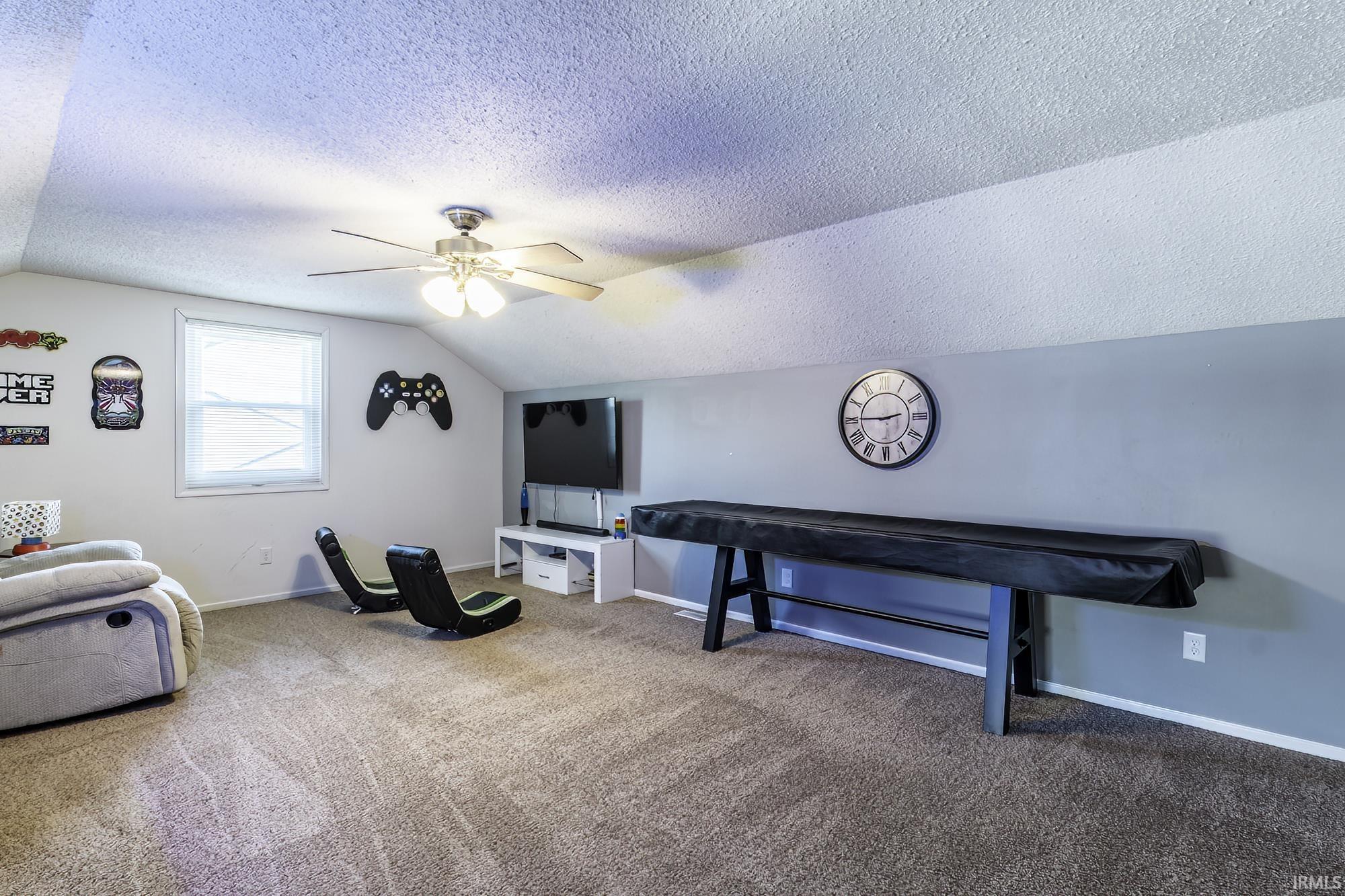 Carpeted room with a ceiling fan, a window, and sloped ceilings