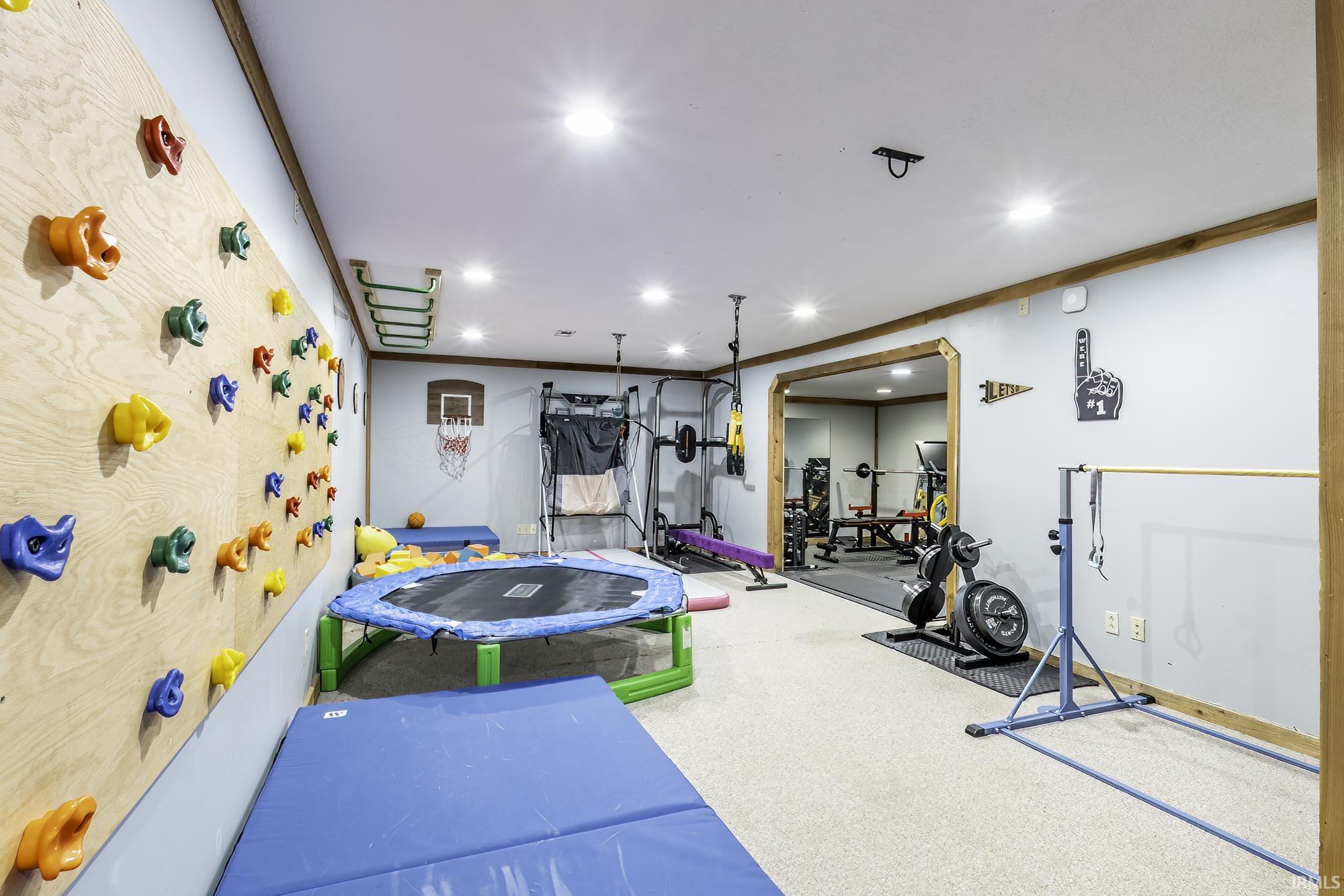 Recreation room featuring a paneled climbing wall, recessed lighting, and wood trim accents