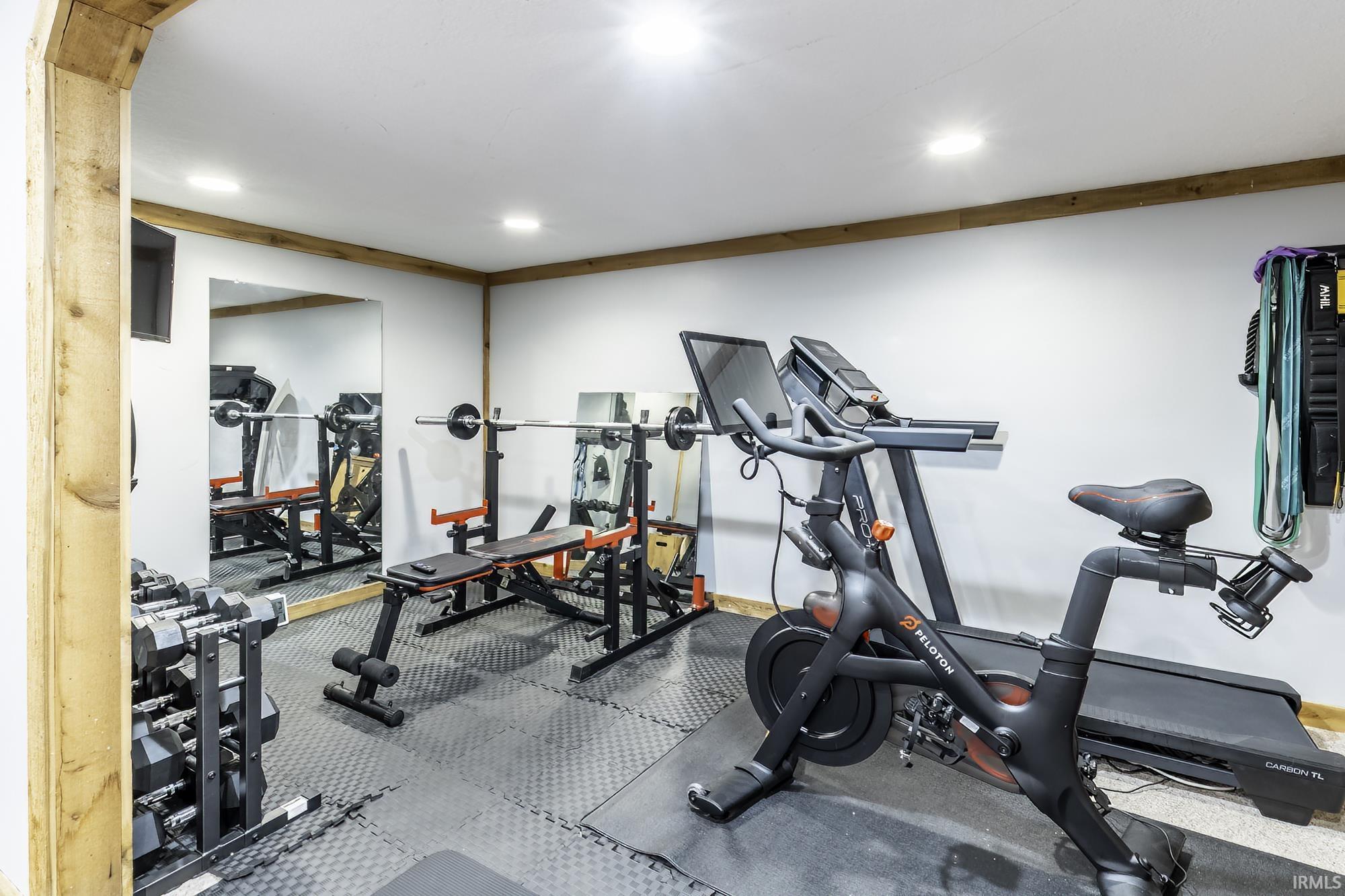 Dedicated fitness space featuring rubberized flooring, recessed lighting, and mirrored wall panels