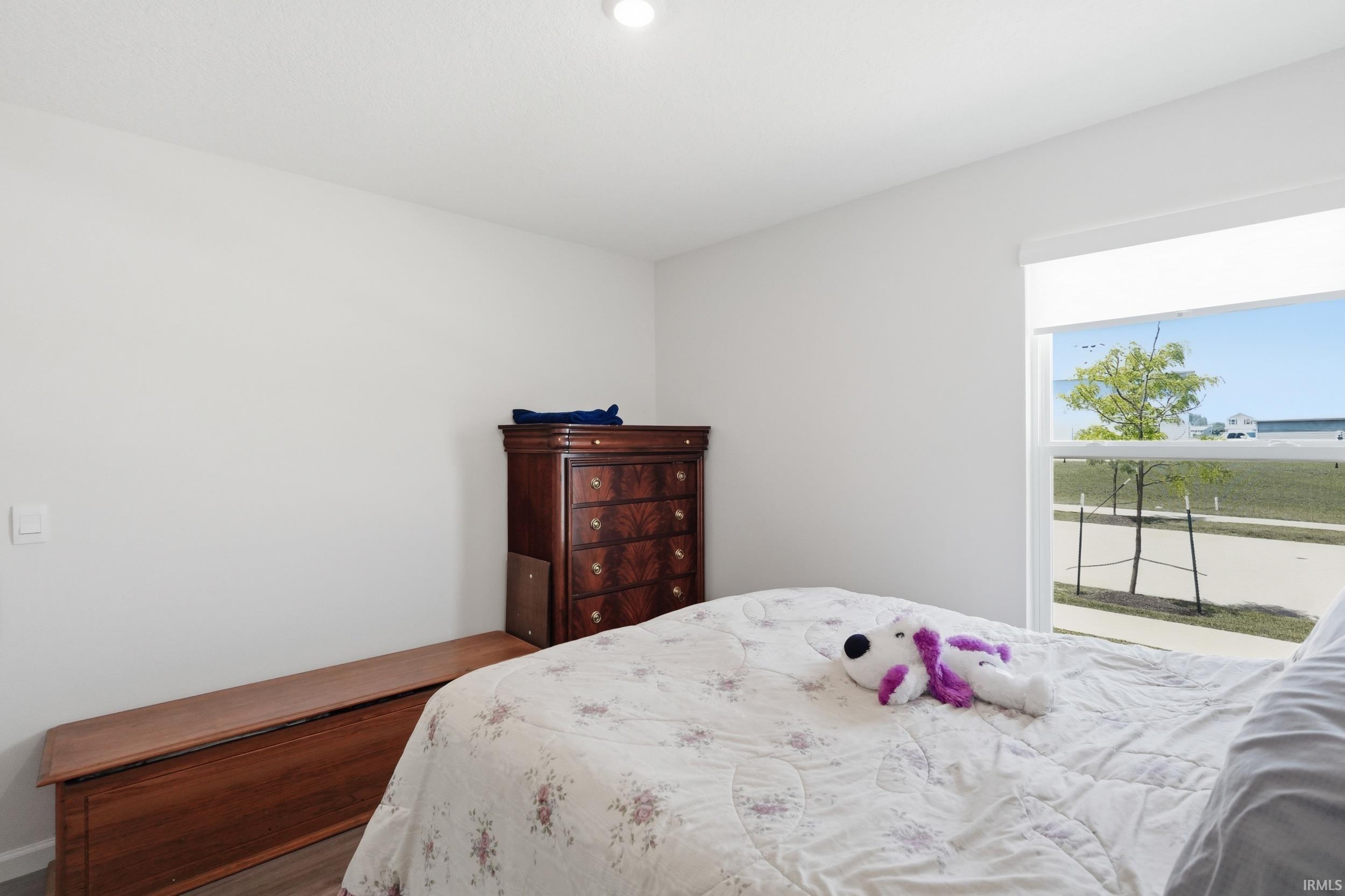 Bright bedroom featuring a large window, recessed lighting, and wood-finish flooring