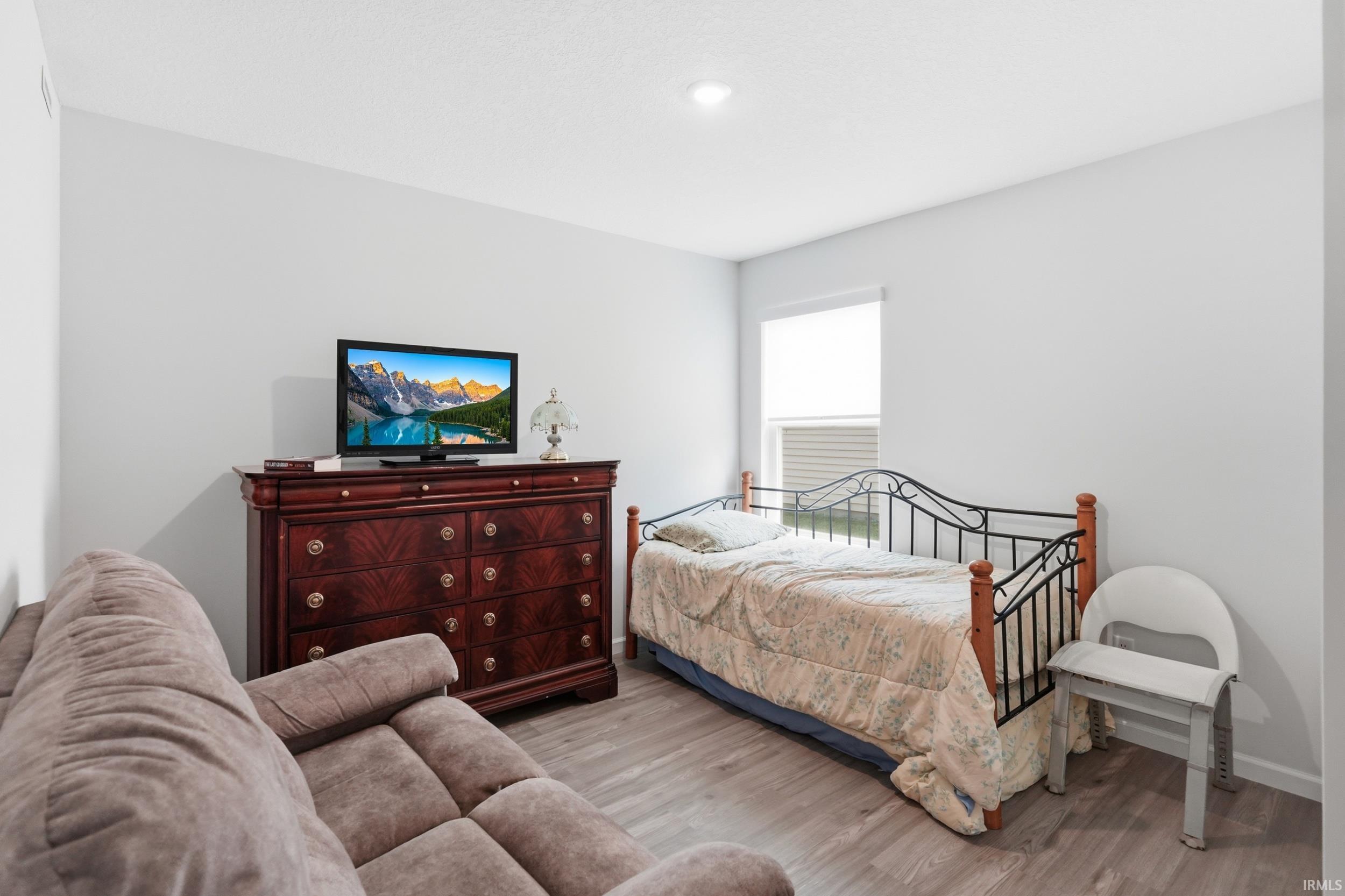 Light-filled interior space featuring neutral wall paint, wood-finish flooring, and a window with blinds