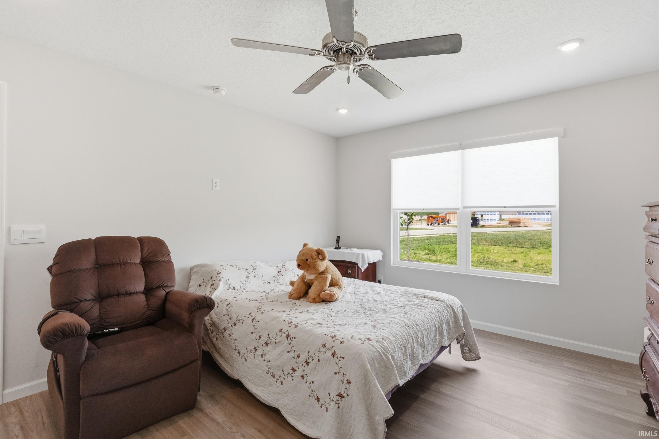 Bright room featuring a ceiling fan with integrated lighting, recessed lighting, and wood-finish flooring