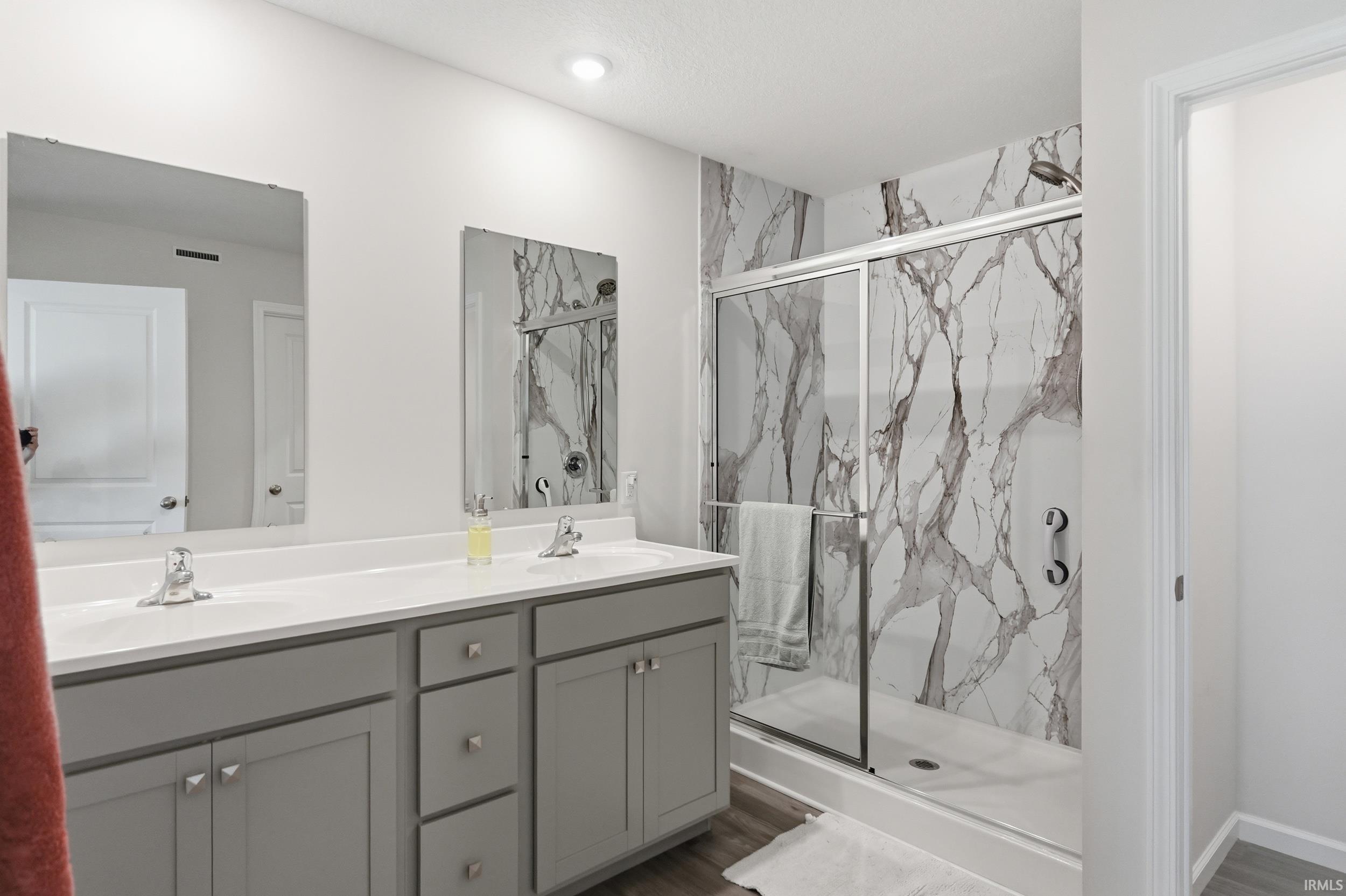 Spacious bathroom featuring a dual vanity with grey cabinetry, white countertops, and chrome fixtures