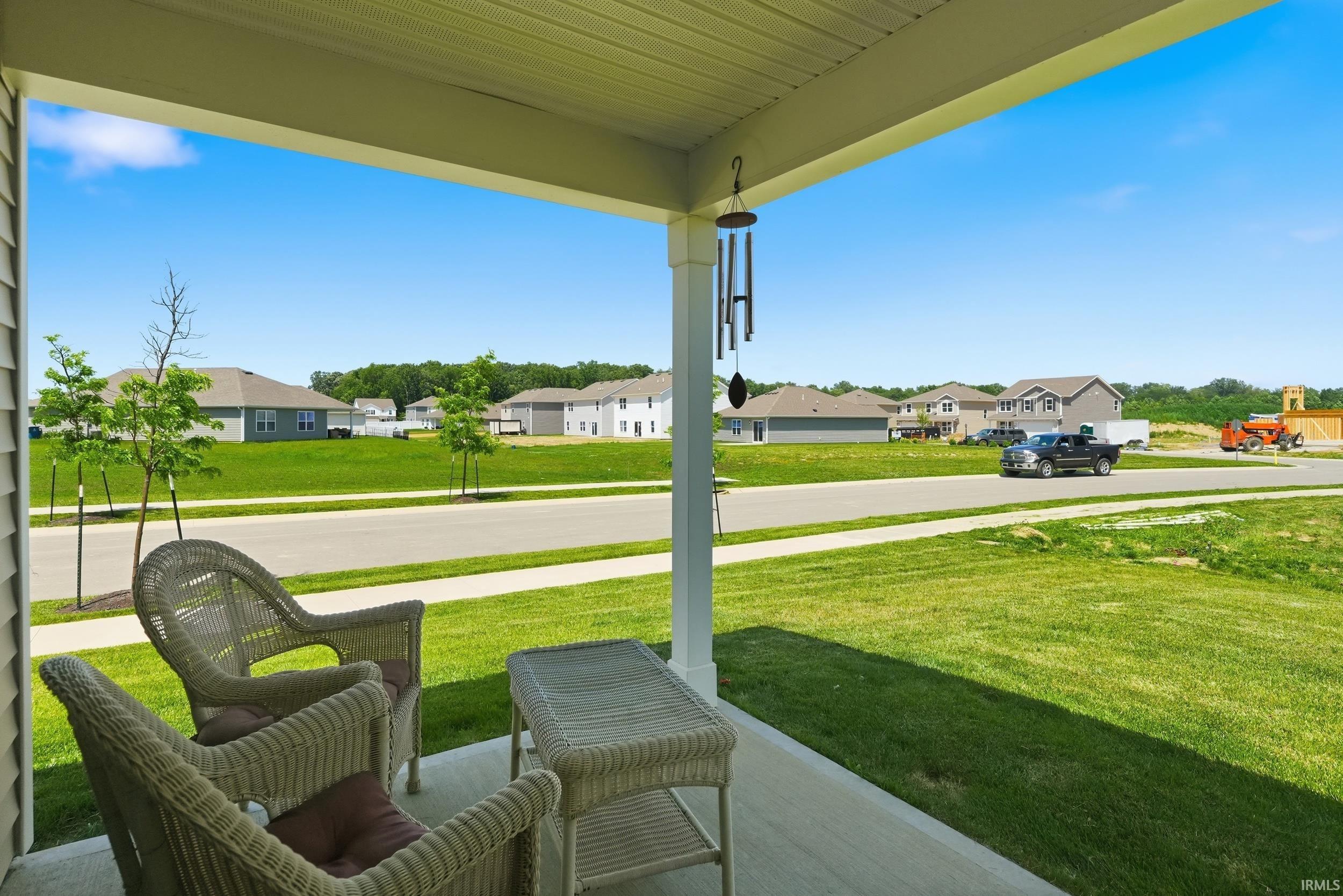 Covered front porch with white columns, light-colored siding, and a concrete patio
