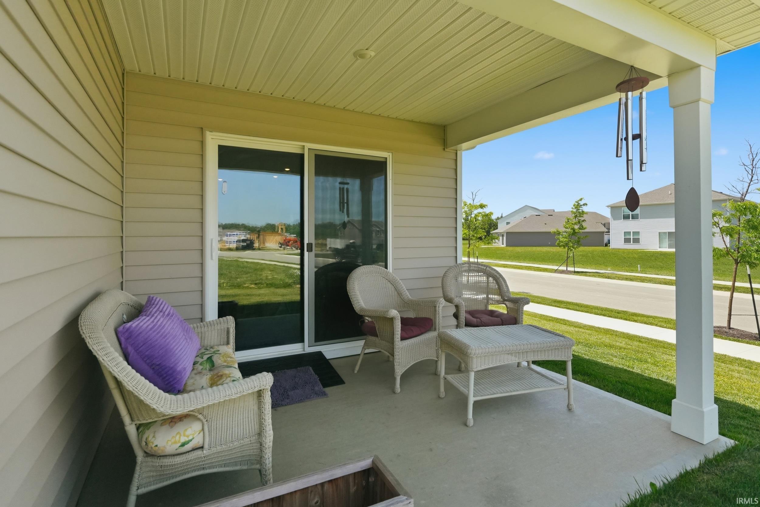 Covered concrete patio featuring siding exterior, white support columns, and sliding glass door access