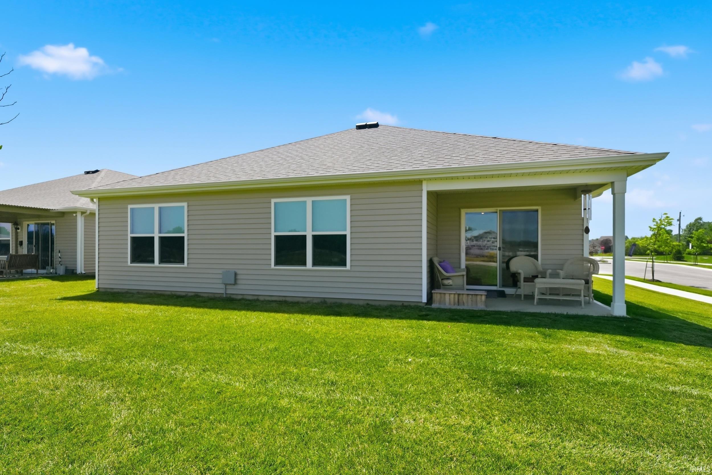Rear exterior featuring a covered patio, sliding glass door, and multiple windows
