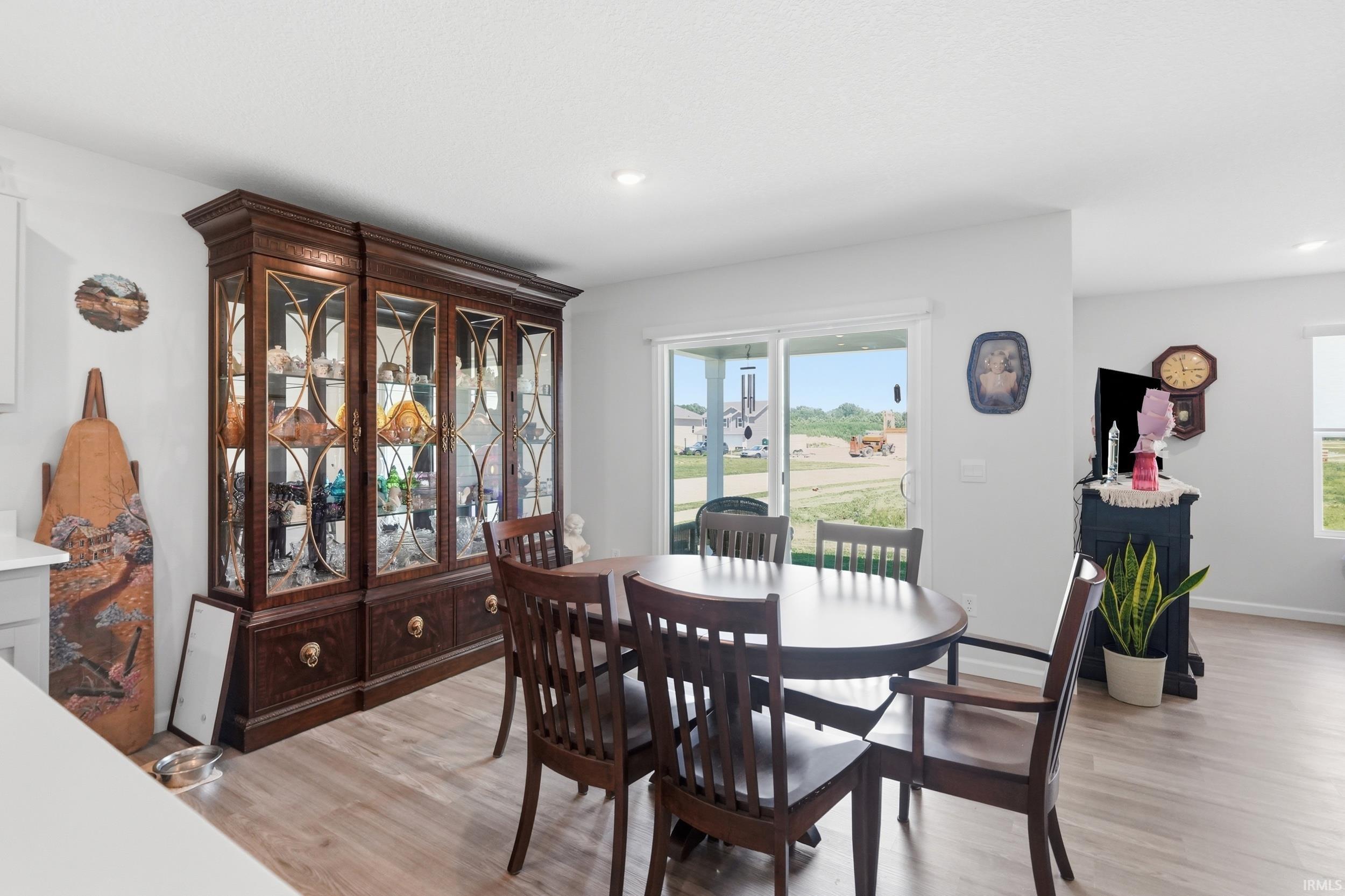 Spacious dining area featuring wood-finish flooring, a built-in display cabinet, and light-toned walls
