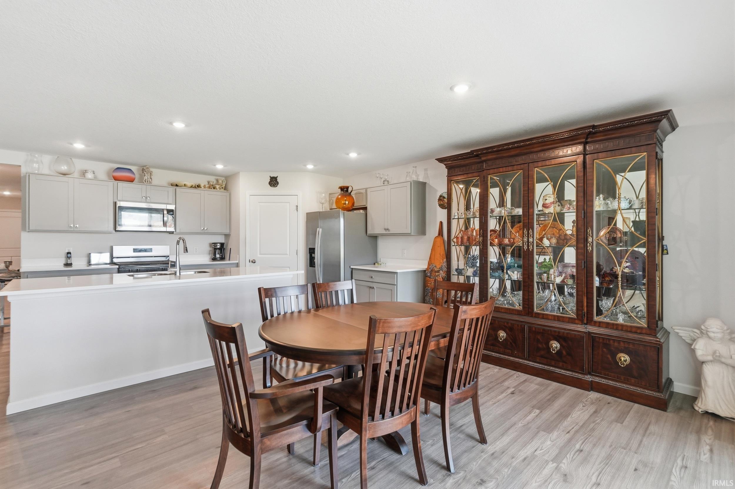 Open-concept kitchen and dining area featuring light wood-finish flooring, recessed lighting, and a kitchen island with a breakfast bar
