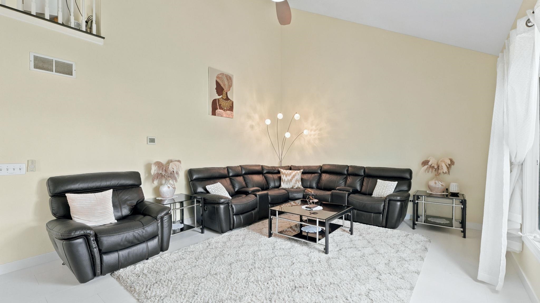 Vaulted ceiling living area featuring a ceiling fan, light-toned wall paint, and white trim