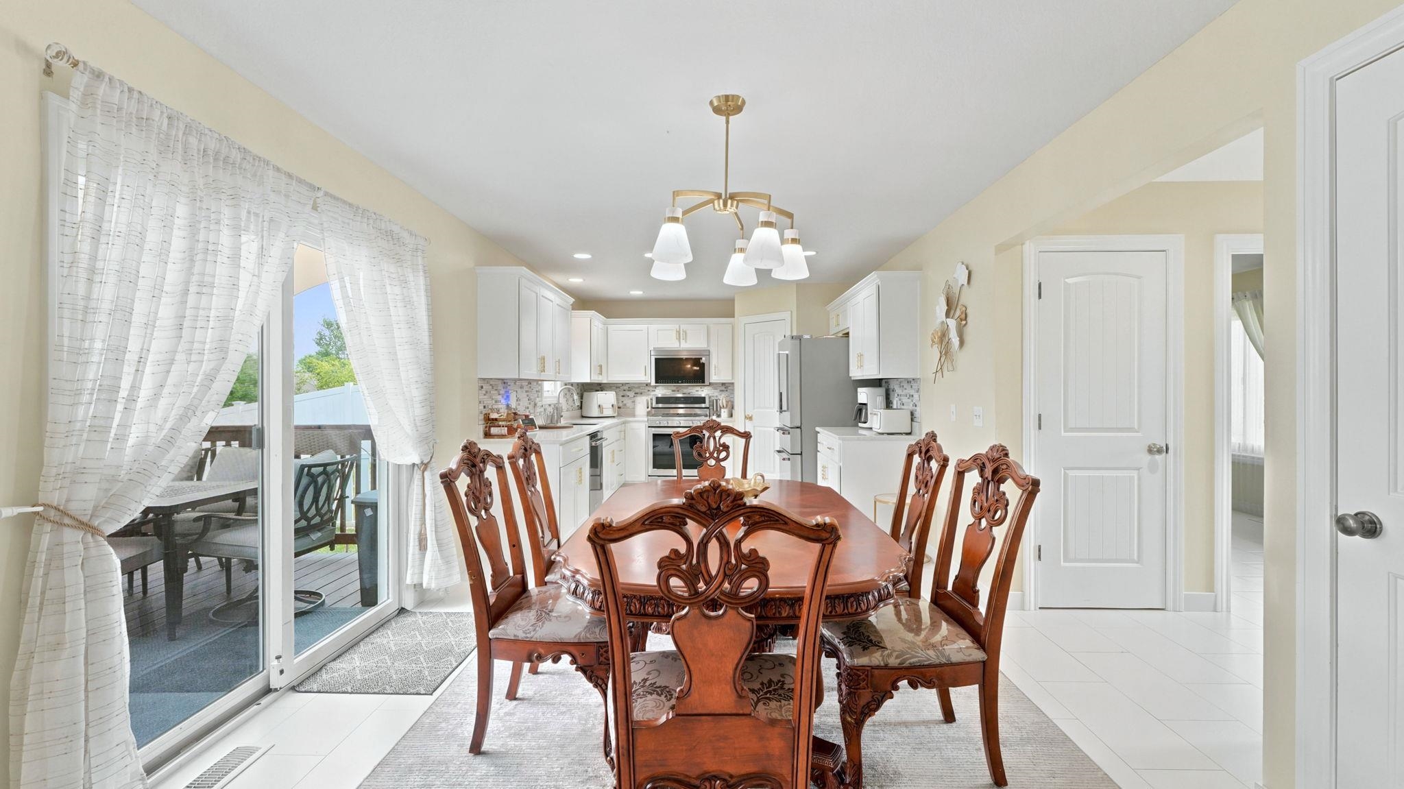 Dining area featuring a contemporary chandelier, light-toned walls, and white tile flooring